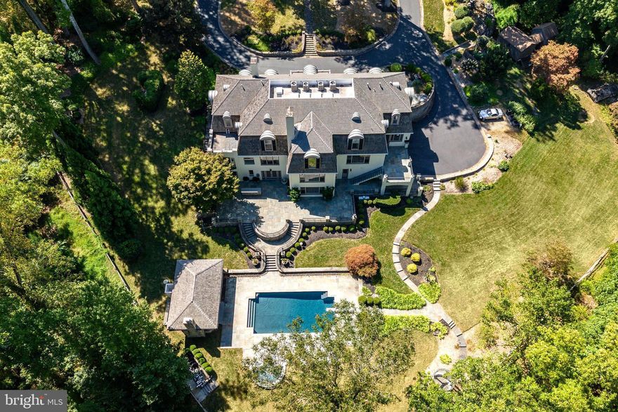 Refreshed and back on the market! 24 Lakewood Drive is a stunning 7 Bedroom, 6 Full Bath, 3 Half Bath, French Country residence, offering over 12,000 square feet of pristine living space. This private estate nestled on 3.4 acres with lush grounds and meticulous landscaping makes a grand first impression as you enter through the iron gate and up the circular drive with center fountain. Enter into the 2 story Foyer with marble floor, personal elevator, beautiful curved staircase w/ custom iron railings, and a powder room w/ custom landscape mural. The adjacent light-filled formal Living Room features a fireplace w/ intricate wood mantle, custom millwork shelving, hidden wet bar, and floor to ceiling windows that offer impeccable views of the Springton Reservoir. Hardwood floors continue in the formal Dining Room with Venetian plaster walls, crown molding, and crystal chandelier. The gourmet Kitchen with custom coffered ceilings & access to the flagstone patio, boasts granite countertops and top of the line appliances including a double oven, 6-burner Wolf range, two sub zero refrigerators, two Miele dishwashers, and a Sharp microwave drawer in the island. There’s also a butler’s pantry, mudroom w/ built-ins, and convenient Half Bath. The adjacent Family Room & Dining area with sliding doors to the patio create a perfect place to entertain family and friends. A handsome office/study with dark wood paneling, extensive built-ins, and gas fireplace offers a quiet space to work or read. Make your way to the incredible main floor Primary Suite, fully renovated in 2015, with a painted wood floor Foyer that sets the tone for the sophisticated touches found throughout. A fireplace in the Bedroom, “His and Her” bathrooms, each with marble floors, glass showers, & custom cabinetry, an expansive dressing room with “his and her” islands & custom closets, a Juliet balcony, and separate HVAC, make this space the perfect place to start and end your days. Head up the staircase to the oversized landing overlooking the living room, with skylights for an abundance of natural light. The second level offers 6 Bedrooms, 3 Full Baths, and a bonus storage room. Head down to the impressive lower level, designed with entertaining in mind, to find a bar area w/ wine cellar, den, full kitchen, game room w/ beamed ceiling & half bath, exercise room with sauna/steam room, full bath w/ shower, and outside access to the sprawling slate patio. The back yard with multiple outdoor spaces, in-ground pool, hot tub, and pool house w/ stone fireplace, kitchen, & half bath, is truly your own private oasis. No detail has been overlooked in this luxurious home once owned by Phillie’s legend, Mike Schmidt. Just 15 minutes to the airport & downtown, and close to all that Media has to offer, this home is an absolute treat for even the most discerning buyer.