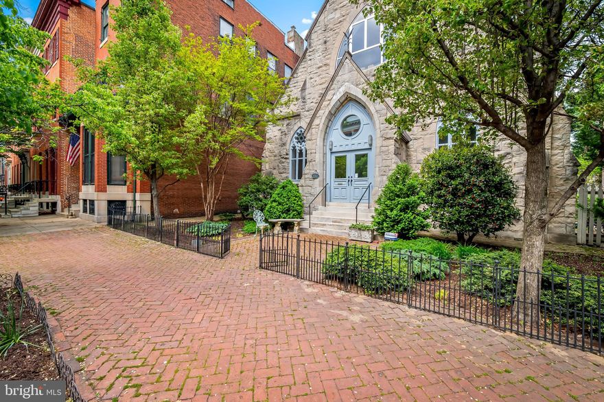 Create the life you love in historic Bolton Hill. Step into a living work of art—where history, architecture, and imagination converge to create a home like no other. Built in 1875, this extraordinary structure has lived many lives: once a church, a community center, a synagogue, and since 2005, a one-of-a-kind private residence. Now, it invites its next steward to continue its remarkable story.

Inside, you'll be captivated by the grand, loft-inspired living space with soaring, light-filled volume that evokes the awe of its sacred past while embracing the openness of contemporary design. Toward the rear, a more intimate tone takes hold: the kitchen and family room radiate warmth and comfort, ideal for quiet mornings or lively gatherings. A chef’s dream, the kitchen features an Aga range, double wall ovens, and abundant storage—all seamlessly integrated into an elegant and functional space. The main level also includes a full bath and a versatile bedroom, currently styled as a cozy den media room.
Upstairs, take the elevator or stairs to a level that balances serenity and spectacle. The primary suite is a showpiece unto itself—beautifully proportioned and thoughtfully appointed. Three additional bedrooms, full sized laundry, and generous storage ensure comfort and practicality.

For a truly poetic perspective, ascend “the bridge” to a sun-lit sitting area beneath the dramatic upper triangle window—a contemplative space that offers sweeping views over the home’s central volume, perfect for reading, reflection, or simply absorbing the beauty of your surroundings.
The lower level offers incredible flexibility: a playroom or gym, a workshop, gallery-style storage, and additional unfinished areas ready for your vision.

Outdoors, the beauty continues. A generous deck overlooks an expansive fenced rear yard, ideal for gardening, or simply basking in the sun. The fenced side yard includes a two-car parking pad, marrying convenience with elegance.

This singular artist’s sanctuary is conveniently located in historic Bolton Hill. Just minutes from Baltimore's Penn Station, this home makes traveling to Washington, D.C., or New York City a pleasure.  Just minutes from MICA, enjoy access to gallery shows, exhibitions, lectures, ArtWalk, and other cultural events. Immerse yourself in Baltimore’s vibrant arts and dining scenes with a short stroll to Meyerhoff Symphony Hall, The Lyric Theater, Theater Project, Everyman Theater, and The Charles. Walkable dining options in Bolton Hill and Station North include Cook House, On the Hill, Llama’s Corner Cafe, Alma Cocina Latina, Foraged, and Le Comptoir du Vin, with even more choices in nearby Mount Vernon.

This is not just a residence, it’s an experience. A rare opportunity to live within art, within history, and within a space that inspires.