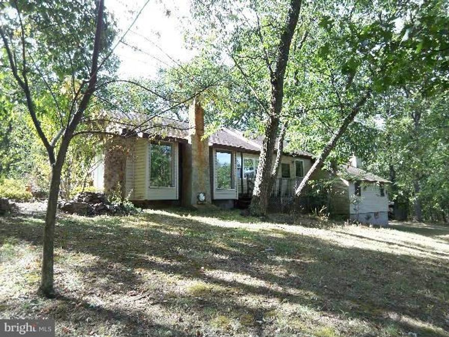 5.57 unrestricted acres with a small chalet home. Native stone features inside and out give this home a unique feeling.  Master bedroom with wood burning fireplace, tongue and groove ceilings, wood floors, and den with woodstove. Winter views of the mountains, a small wet weather pond with outdoor fireplace. Private and secluded in mostly wooded setting.