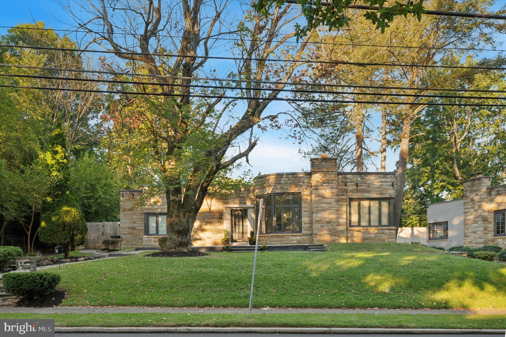 Experience refined one-floor living in this fully renovated rancher-style residence in one of Wynnewood’s most desirable neighborhoods, just across from Penn Wynne Elementary. Enter through the foyer to discover hardwood floors, recessed lighting, crown molding, and subtle touches of classic charm that hint at the home’s original character. The formal dining room offers an elegant setting for hosting dinner with friends and family. The meticulously designed kitchen includes white shaker cabinetry, quartz countertops, herringbone backsplash, stainless appliances, and a greenhouse window that fills the space with natural light. An adjacent laundry room, with included front loading washer & dryer, elevate everyday living. Convenient, powder room is perfect for guests. An expansive living area exudes warmth and grandeur with its marble gas fireplace, custom built-ins, contemporary lighting and full wet bar within an arched niche create an inviting hub for entertaining.. The sunroom, a bright and serene retreat, features a modern twist with stylish diagonal wall panels, blending contemporary design with comfort and elegance. The owner’s suite, with ample closet space, features a cozy en suite with soaking tub and designer vanity. For guests or in-laws, a spacious bedroom with double-door entry and its own fireplace creates a private, inviting retreat. Two additional secondary bedrooms are designed for comfort and functionality. Beautifully designed hall bath with walk-in shower, new vanity and new tiled flooring. Outdoors, a fenced backyard offers a private escape for gatherings, summertime grilling, playtime with children on the included play set, or relaxation, Convenient two-car garage and ample parking for guests. Set across from Penn Wynne Elementary and just moments from premier shopping, dining, and major routes, this home blends luxury, character, and convenience in one remarkable offering. Don’t miss the opportunity to make this exceptional home yours—schedule a showing today and submit your offer on this Wynnewood gem!