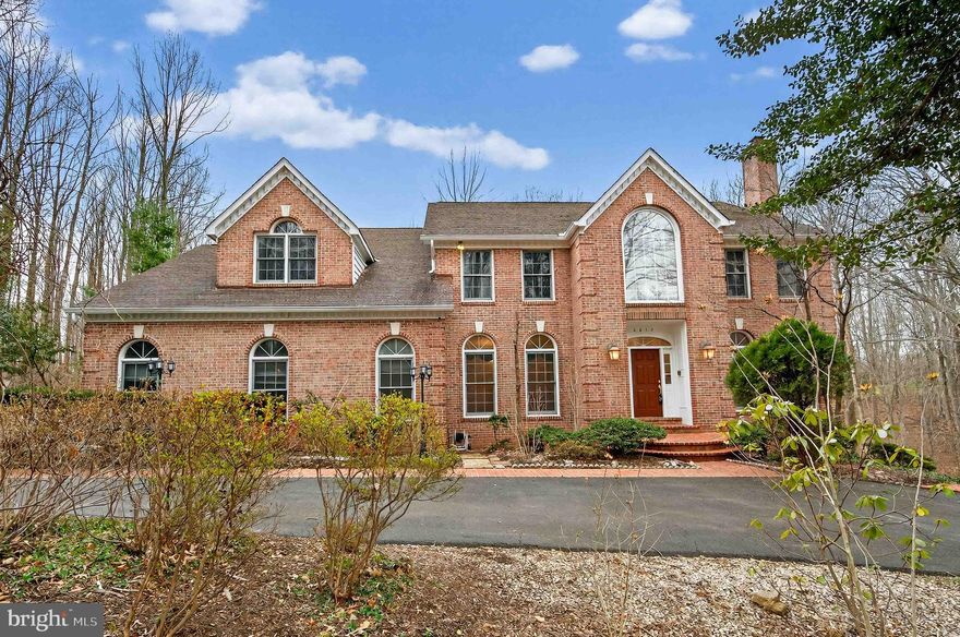 A rare opportunity awaits to own one of Clifton’s most distinguished estate homes. This extraordinary 7,400 sq ft all‑brick residence offers 5 bedrooms, 5.5 bathrooms, and an unmatched blend of luxury, privacy, and tranquility—just minutes from major amenities and the timeless charm of historic Clifton.

A dramatic two‑story foyer sets the stage with a grand crystal chandelier, sweeping circular staircase, exquisite woodwork, and extensive custom moldings that immediately convey refined sophistication. The formal living and dining rooms are gracious in scale and beautifully appointed, with expansive windows framing picturesque views of the surrounding landscape.

Just beyond the living room, a light‑filled private study provides an ideal retreat for work or quiet reflection, enhanced by an elegant chandelier imported from the Czech Republic.

At the heart of the home, the expansive family room features a striking stone wood‑burning fireplace and a well‑appointed wet bar—perfect for entertaining. Flowing seamlessly from this space is a stunning sunroom that overlooks the private wooded grounds, creating a serene backdrop for everyday living.

Outdoor living is exceptional, with a large open lawn ideal for soccer games, gatherings, and celebrations. A brand‑new wraparound deck invites morning coffee, alfresco dining, and relaxed enjoyment throughout the day.

The bright, beautifully updated kitchen boasts brand‑new appliances, elegant granite countertops and flooring, and four oversized skylights that bathe the space in natural light—creating a warm and inviting atmosphere for cooking and gathering.

Additional main‑level highlights include a spacious laundry room, a convenient secondary staircase, and an oversized garage with a large bonus area perfect for a workshop or additional storage.

The upper level features two exceptionally large primary suites—an uncommon and highly desirable luxury—along with two additional generously sized bedrooms. Three of the bedrooms include beautifully renovated en‑suite bathrooms, while a tastefully updated hall bath serves the fourth.

The walk‑out lower level is equally impressive. With a fifth bedroom and full bath, it offers excellent potential for a luxurious in‑law or guest suite. This expansive level includes a large living area with a wood‑burning fireplace, a kitchenette with bar seating, and three additional oversized rooms that provide remarkable flexibility—ideal for a home theater, fitness studio, spa retreat, craft room, or hobby space.

One of the few all‑brick estate homes in the Clifton area, the property also features an impressive circular driveway accommodating up to 24 vehicles—perfect for hosting large gatherings and special events.

Recent upgrades include a new roof, new HVAC system, new water heater, and beautifully renovated bathrooms. The home is also generator‑ready, with infrastructure already in place.

Enjoy peaceful walks along this quiet street, where a picturesque pond across the way enhances the serene natural setting—offering a sense of retreat while remaining just minutes from the restaurants, shops, parks, and conveniences of historic Clifton and the greater Northern Virginia area.