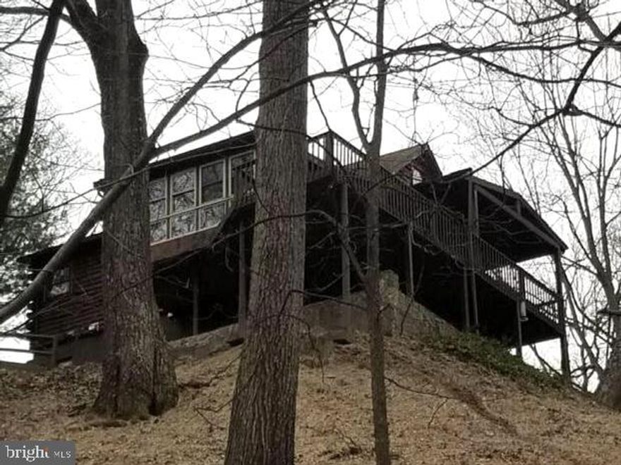 MILLION DOLLAR VIEWS, so many possiblities, could be a great Air BandB, or 2nd home or full time peaceful location!  So much to offer with this property....3 lots convey with the property total of 3.85 acres and 2 lots lines are adjact to the Sleepy Creek Wildlife Management area 22,928 public acres with which is a haven for hunters, fisherman and hikers.  Also, within the sub division to mention some admenties is the Sleepy Creek Lake with beach area for swimming, fishing, canoe/kayaking, Tuscarora hiking trail and a ball field would be great for the friends and family fun with pavilion for picnics and gatherings.   This home  has been loved and cared for and in the family since back in the 60's when they purchased the property.  Then the home in 1980.  This is a true logged home home with logs from the property, many details in the craftsmanship with handmade handrails, medicine cabinets,  chestnut wood floors.  When you arrive to the property you are going to appreicate the private location at end of the lane, and then as come into the drive make sure to check out all the outbuildings.....detatched garage, the huge workshop with electric, 2 wood sheds, an other big shed currentyly used as a garden shed and then the green house with electric and phone land line, and system set up to feed water to the greenhouse from the well.  You will love the beauty of all the rock and stone flower beds and walk ways.  Now, let me tell you about the house.... as you enter the home to a foyer room with lots of windows and wood finishes and stone top to bottom to start,  then to the great room you find the stone gas fireplace, cathedral ceilings and chestnut wood floors, the wall of  windows/doors to enjoy the views from inside, then sunroom heated with windows to enjoy all year long.  (Sunroom has even been used as a bedroom in the past to wake up to the views).  On the main level you will also find the primary bedroom with pocket doors in the front of the home, in the hall is the full bath with claw tub, large vanity.  Be sure to step out to the large deck of the main level and see the where you can enjoy the wildlife and views as you gaze over the property.  Make sure you check out the loft, could be used as bedroom or great office.  Now down to the lower level,  you will find another full bath with stand up shower, laundry room and storage room, some build in shelving in lower level, wood burning stove, large area for 2nd living room or recreation room, the country kitchen with lots of cabinets and pantry.  Then be sure to step out to the lower level stone wrap around patio, again great area to enjoy the beauty of the views and property.  Another cool room not to miss is cold storage room on right as you come out to patio.  So much to see and view....Come view soon before you miss out!!!  Still many boxes throughout the home as they clear out many years....please excuse will be finished prior to  settlement.