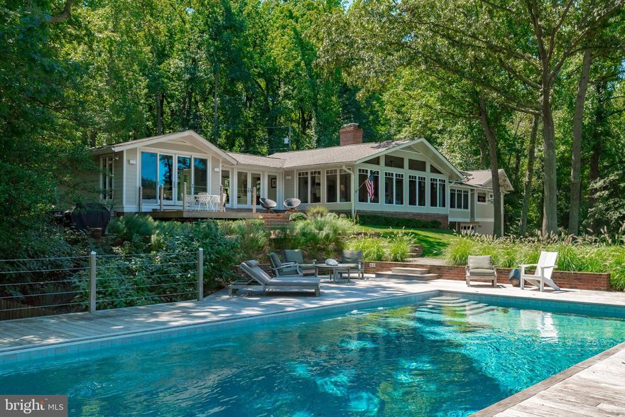 Possibly the largest and most private parcel in Bay Ridge, 197 West Lake Drive presents a rare opportunity to own a spectacular coastal waterfront property in one of Annapolis' most popular neighborhoods. Just minutes from the United States Naval Academy and the boutiques, shopping, and restaurants of historic downtown Annapolis, this inspired, contemporary, light-filled 4BR/3BA home is located down a long, private drive on a peaceful 2-acre lot with 440 feet of sheltered water frontage. Sustainably landscaped, the expansive lawn slopes gently down to the water with sweeping views of Lake Ogleton, while the protected, private pier, buffeted by undisturbed wetlands, provides unlimited access to the Chesapeake Bay. Grandfathered, custom boat house with boat lift and waterside saltwater pool. Separate waterfront outbuilding with loft allows for seamless indoor/outdoor living. Completely remodeled gourmet kitchen connects to great room with wood-burning fireplace, full zinc-topped wet bar with copper sink and ice maker, and soaring, vaulted ceilings ideal for entertaining. Radiant heated flooring in foyer, kitchen, and primary bath. Partially finished basement with walk-out family room and lots of storage. New, oversized, detached 2-car climate-controlled garage with electric vehicle charger. New generator with extended running fuel powers the entire property. This home has only been owned by two families and has been lovingly maintained and updated with many significant improvements. The home is also notable for being featured in the 2008 Ridley Scott film Body of Lies starring Leonardo DiCaprio and Russell Crowe. Home to the Chesapeake Bay Foundation, Bay Ridge is a very active community with many amenities and opportunities to be social year-round, like the annual Fourth of July Parade. Great walkability and scenic routes for cycling. Ride your golf cart to the marina, clubhouse, and ball courts, including pickleball! There's something for everyone in this historic neighborhood. Rt. 50 and 97 provide direct access to Baltimore, BWI, Ft. Meade/NSA, Washington, DC, and the Eastern shore. Welcome home!