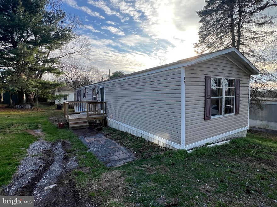 Welcome to Trailer #14 in Taylorsville Mobile Home Community. This rare 2-bedroom, 2-full-bath mobile home in Mount Airy offers 14’ x 66’ of comfortable living space, complete with vaulted ceilings, an open floor plan, and central air. Recent updates include new hallway stall shower, new carpet, newer water heater, and newer front porch deck, and rear deck has been fixed up. Step inside through the foyer to find a spacious living room that flows into the kitchen and dining areas. The kitchen features a ceramic tile backsplash, gas range, dishwasher, refrigerator, hardwood flooring, and plenty of cabinet and counter space. Just off the kitchen is the laundry room equipped with a full sized washer & dryer, with an additional exit to the rear yard. The primary bedroom features an attached full bath with a double vanity, separate shower, and large soaking tub. (The tub is functional—previous leak has been repaired—but could be removed if you prefer more space.) On the opposite side of the home, you’ll find the large second bedroom with a walk-in closet. The hall bath has just been updated with a new stall shower. Outside, has two driveway parking spaces, gardening space, and a storage shed. Lot Rent is currently $800/month and includes water (community well), sewer, trash removal, road and common area maintenance, and property management. Park approval is required through an application with the community managers. Mobile homes in Mount Airy are hard to find—don’t miss this opportunity to own your home at such an affordable price.