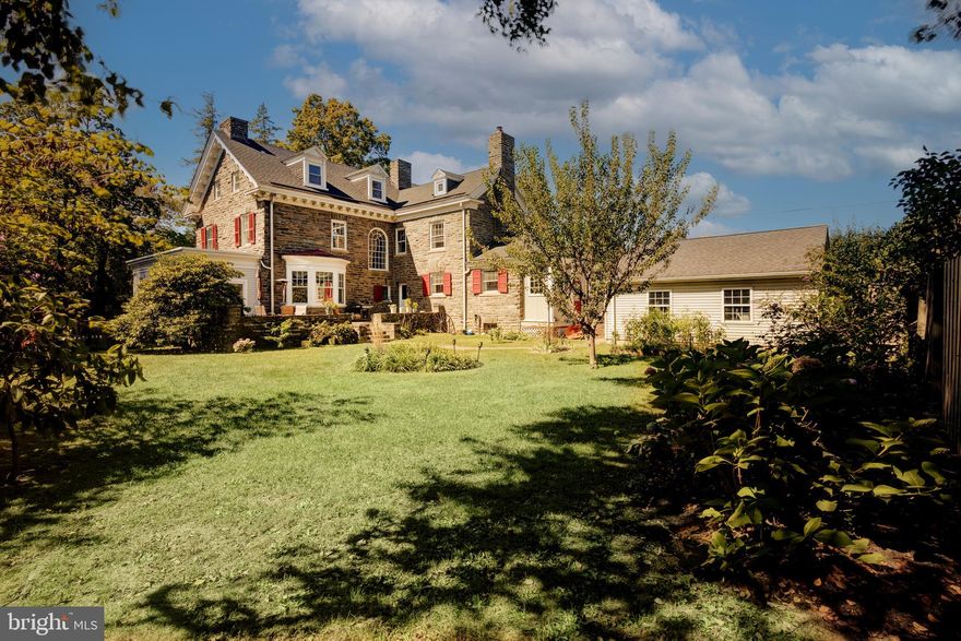 Situated in sought-after Wyndmoor,  this stately 6-bedroom, 4.5-bathroom center hall Wissahickon Schist colonial home offers a blend of historic charm and modern luxury.   Beautifully proportioned, this is a grand residence and a testament to timeless craftsmanship. Throughout the home, you'll find original features, including hardwood floors with mahogany inlay, extensive crown molding, and wood trim that all add character. Step through the vestibule into the entryway, and your eyes are immediately drawn to the elegant staircase with graceful Palladian window that bathes the space in natural light. To the right of the entryway, through original pocket doors, the living room extends the length of the home, and features large windows at each end that frame views of the gardens around the home. The focal point of the  room is the gas fireplace, adding warmth and charm to your gatherings. Double French doors lead to an enclosed original side porch, perfect for an office, reading room or additional living area. The porch offers convenient access to the rear stone terrace. To the left of the entryway, the spacious dining room, also featuring a statement fireplace, offers generous entertaining space, making it ideal for hosting dinner parties and family events. The adjacent renovated kitchen boasts custom cabinetry, granite countertops, and stainless steel appliances, with ample space to eat-in, either at the breakfast bar or next to the cozy gas fireplace. Off the kitchen, a spacious laundry/mudroom provides practical space. Outside, the stone terrace overlooks the gardens and provides an ideal spot for a quiet read or outdoor entertaining. Step down from the terrace into the fully fenced rear yard with koi pond, mature flowering trees and shrubs; a tranquil space for gardening and relaxation. The original stone wall adds privacy, and a newer two-car garage sits conveniently near the back door. The second floor of the home offers a light and spacious landing. The primary bedroom boasts a fireplace and ensuite bathroom with original tilework. Two additional sunny bedrooms provide access to full bathrooms, each with original tilework and clawfoot tubs. These bedrooms also showcase unique beveled borders in the wood floors. The third floor presents a self-contained suite of rooms with a variety of uses, guest suite, au pair suite, home office space – you choose! Two bedrooms share a common area, perfect for a study or lounge, plus an additional bedroom and full bath. There’s a spacious built-in original cabinet on the third floor landing, with a large walk-in floored attic space to meet all your storage needs. The unfinished basement offers further storage space, while a new roof installed in 2021 is a welcome upgrade. It’s an easy 10-minute stroll to local amenities, including popular Wyndmoor spots: Locals Coffee, Enzo Pizzeria, and Captain Andy’s Market and the regional rail station. Chestnut Hill is conveniently located just a mile away, offering even more shopping and dining. Don't miss your chance to make this Wyndmoor treasure your forever home. Schedule your viewing today!