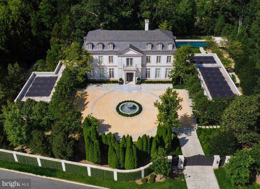 Sited along revered Foxhall Road, at the highest point in Washington, sits one of the finest residences ever constructed in the Capital Region. Inspired by the Château du Grand-Lucé in central France, an undisputed all-star team of artisans — interior designer Thomas Pheasant, developer Michael Banks, architect David Jones, and landscape architect Richard Arentz — have collaborated over the course of three years to create an estate whose unrelenting splendor harkens back to an era of handcraftsmanship extremely rare in contemporary times. The discreet walled and gated entrance opens to reveal a meticulous front garden and paved cobblestone motor court, centered by a bubbling marble fountain. Indiana Limestone punctuates the stucco on the masonry facade, topped by a handsome slate mansard roof. In perfect symmetry and proportions, tall windows and arched dormers above replicate the home’s inspiration in the most exacting manner. Entering the property is an occasion in and of itself. Beneath the limestone portico is a set of arched double doors, parting ways to welcome guests into a breathtaking, double-height rotunda with a curved floating stair that serves as a functional work of art. Underfoot, imported Italian Niro Marquina marble radiates toward the formal rooms. The living room spans almost the entire width of the property and features a custom bar balanced by a floor-to-ceiling temperature-controlled wine display, lined with French doors framing breathtaking views of the terrace and rear garden. Countless artisans from across the country were enlisted to create the custom-cast bronze metalwork and plasterwork found throughout the home. This exacting level of detail extends to every aspect of the property. The kitchen is a textbook example of minimalism, with its continuous European cabinetry and slabs of marble only accented with brass hardware. Miele, Wolf, and Subzero appliances with Waterworks hardware come together in a harmonization of form and function. Ascending the rotunda stair reveals the principal bedroom. A private limestone terrace overlooks the grounds with unobstructed westward views beyond. A marble corridor traverses the space, bridging the two primary baths and expansive dressing rooms. Each wing has a distinct theme, boasts heated floors, and is drenched in marble. Additional ensuite bedrooms are found on the third level, tucked under the mansard roof. The lower level showcases equally impressive outdoor views with its sweeping wall of floor-to-ceiling windows framing the verdant tree line and private rear grounds. Absolute black granite on the floors, walls, and ceilings adds a striking touch, while the plush cinema, spa, and fitness facilities more than befit a home of this caliber. A professional two-story indoor sports court and golf simulator complete the space. Landscape architect Richard Arentz wanted the landscaping to be as important as the home itself. As such, he spent years meticulously engineering, hardscaping, and installing countless mature plantings from all over the country that evoke a rare sensation of total privacy and tranquility, a feeling intensified by the beautiful simplicity of the estate grounds. The tiered garden reveals a fifty-six-foot heated pool, and just beyond the pool, a private chipping and putting green. Internal systems are all of the highest capacity. Highlights include a whole-home seventy-two-kilowatt generator, eight geothermal wells providing twenty tons of cooling capacity, and twin three-car garages.  Strategically positioned mere minutes away from the White House, embassies, upscale dining, and vibrant entertainment hubs, this estate offers unparalleled convenience. Undoubtedly, 2400 Foxhall Road stands as an extraordinary testament to unwavering quality, representing one of the most exceptional properties ever presented in the Mid-Atlantic.