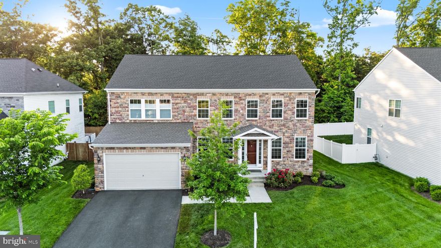 Welcome to 8934 Hubbard Way in Laurel Hills Crossing, Lorton. Five bedrooms, five and a half baths, 4,459 finished square feet across three levels, all-stone front, two-car garage. The kind of home that buyers wait months for in this community.

The main level lives big and lives smart. A two-story family room with a marble-surround fireplace sits at the center, with floor-to-ceiling sheers and a statement staircase. Wide-plank LVP runs throughout. The kitchen has white shaker cabinets with gold hardware, granite counters, gas cooktop, double wall ovens, French door refrigerator, walk-in pantry, and a dark contrasting island with seating under twin gold and crystal pendants. The breakfast nook opens to a composite deck that overlooks woods, not neighbors.

The formal dining room features wainscoting, crown molding, and a statement chandelier. There is a separate formal living room and a main-level in-law suite with a private full bath, which gives you real single-level living for guests, a parent, or anyone who needs to skip the stairs. Off the mud room is the bonus flex space the current owners call the Costco Room, with a built-in wrap-around wooden workspace and storage below. A powder room and Graber Blinds throughout finish out the main level.

Upstairs, the primary suite is a true retreat with windows on two walls, blackout Graber Blinds, a crystal fan chandelier, dual walk-in closets plus a third accessory closet, and a spa-style en-suite. Three more bedrooms share two full baths, both with granite vanities and espresso cabinetry. Laundry is on the upper level where it belongs.

The lower level is what sets this home apart. The main rec room has space for a sectional, wall-mounted TV, and a linear electric fireplace, plus a full wet bar with white shaker cabinets, granite counters, a peninsula with seating, beverage fridge, stainless dishwasher, and three tiers of display shelving. The game room is built for a poker table, with a custom wine wall and lounge seating. A lower-level bedroom with walk-in closet sits next to a full bath. A private home gym is already set up. Built-in Sonos speakers wire the whole level.

Laurel Hills Crossing is one of Fairfax County's most well-kept communities. Tot lots, two pet relief areas, open green space, and Laurel Hill Golf Club inside the community footprint. The Workhouse Arts Center and Bunnyman Brewery are directly across the street. South Run Park, Occoquan Regional Park, and the Laurel Hill mountain biking trails are minutes away.

Schools: Silverbrook Elementary, South County Middle, South County High. All within the South County pyramid and all highly rated within FCPS.

Commute is built for Northern Virginia life. I-95, Fairfax County Parkway, Route 123, and the Lorton VRE station all within reach. Fort Belvoir is minutes away. Springfield Town Center, Whole Foods, Trader Joe's, Wegmans, and Potomac Mills all close by.

Stone front, three finished levels, in-law suite on the main, full bar and game room downstairs, and a private home gym. Walk through it once and you will understand the price.