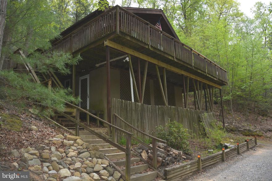 Truly unique property in an interesting mountain community.  Used as a weekend/vacation home by the present owner, the home has been  professionally renovated and certainly could qualify as a full time residence.   The great room has a corner, stone, woodburning fireplace, combined with the kitchen and dining area creating an open concept with a beautiful wood finished cathedral ceiling.  Walk through front sliders to a 3 sided wrap around deck.  There are 3 bedrooms/2 baths with the main bedroom containing one of the full baths.  Engineered wood flooring grace much of the flooring with 2 bedrooms carpeted.  On the ground level is a neat "man-cave", with workshop and storage.  The laundry is in this lower level although there is a hookup  in the hall above.  There is central air & heat.  This 5 acre lot extends across Ritter Valley Drive and has about 250' frontage on Dillons Run, a state stocked trout stream.  The land is split by the road with maybe 2 acres on the house side and 3 acres on the creek side.  The land is mostly wooded, and very usable land on the creek side with just a slight downhill to the creek.  Ritters Hidden Valley doesnt have a formal HOA, but a Committee (homeowners)  collecting annual dues for road and park maintenance.  There is a swimming lake w/beach, playground, picnic pavilion, tennis court and stocked fishing lake.  You can also enjoy your ATVs on the over  17 miles of community roads and shooting/hunting is allowed on your lot. This is a rare offering as not much becomes available in this community.