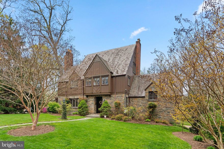 Discover this exceptional English Tudor home nestled on three lots in the highly sought-after community of University Park. Boasting remarkable curb appeal, including a Vermont slate roof, this unique residence welcomes you with an enchanting charm that captivates from the moment you step inside.
The large living room is the heart of the home, featuring a cozy gas fireplace surrounded by exquisitely detailed woodwork, including raised paneling, moldings, and fluted pilasters adorned with elegant rosettes. The rare combination of sycamore and gum wood delivers a warm and inviting atmosphere. The beautifully designed kitchen showcases impressive cabinetry and distinctive decorative touches painted by an artist, making it a culinary delight. Additional features include an extended granite counter for casual dining and fluted wood pilasters that elegantly frame the refrigerator. Step through the dining room's French doors to a generous deck overlooking lush azaleas that bloom beautifully in spring. The adjoining three-sided screened porch, adorned with arches and a ceiling fan, is perfect for relaxation and entertaining.  A cozy family room, finished in knotty pine paneling, provides a sense of warmth with its wood-burning fireplace and built-in bookshelves. The home offers a total of four bedrooms and two baths on the second floor, showcasing charming features such as window seats and authentic leaded glass windows. A permanent staircase leads to a spacious attic equipped with two windows, electricity, and existing studs, offering potential for conversion into a private office or playroom. The versatile lower level features durable Pergo flooring, another wood-burning fireplace, and a full bath, along with a sump pump and an exterior exit for convenience.  Enjoy the pristine condition of oak floors throughout, along with an integrated alarm system and Ring cameras for added security.  With it's close proximity to Whole Foods, Burton’s Restaurant, Trader Joe’s, Denizen's, Gold's Gym, etc., and the vibrant University of Maryland, this home is ideal for buyers seeking a timeless forever home with both character and convenience. Don’t miss the opportunity to own this architectural gem—schedule a showing today!