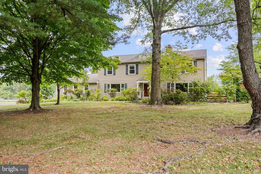 Drive down a quiet country road to be greeted by this charming colonial nestled on over 2 acres of tranquil Bucks County land. Conveniently located within Solebury Township for an easy commute, this 5 bed, 3 bath home warmly welcomes you from the time you step inside. As you approach the front of the home, you will admire the flagstone walkway, colorful garden beds and mature trees, which all contribute to its intriguing curb appeal. Enter the spacious foyer adorn with custom corner bookshelves to find a meticulously maintained interior featuring original hardwood floors and neutral tones.  The entrance is flanked by the cozy living room boasting a brick wood burning fireplace and sizeable dining room, both decorated with custom crafted built-ins.  Discover many noteworthy features as you make your way around the amazing space including the wide entrance ways, special wall enhancements and the abundant natural light from the perfectly positioned windows and doors. The open gourmet kitchen, with its serene garden views, opens through a set of French doors to a large patio area, creating a seamless flow between indoor and outdoor living. The eat-in kitchen is a chef's dream, boasting rich cabinetry, attractive quartz countertops, a butcher block topped center island, coordinating tile backsplash, new gas range and a useful pantry closet for storage. Adjacent, the family room with its second wood burning fireplace, offers a warm and inviting space to gather or unwind after a long day, especially during the crisp evenings. A hallway off the kitchen houses a convenient laundry room, full bath, and second entryway with easy access to the 2-car garage and backyard rounding out the main level. Retreat upstairs to the roomy primary suite with ample closet space and ensuite full bath featuring tile flooring, newly updated vanity,  walk-in shower and dressing area. Four additional bedrooms, each sharing a remodeled stylish hall bathroom complete the second floor. The lower level, currently used for a gym, provides additional living space and awaits your ideas!  Outside, the fully fenced-in backyard is surrounded by mature landscape for character and privacy while a sizable patio invites you to relax and enjoy the sounds of nature and tranquility. A neighboring barn on the property offers versatility—originally utilized for raising horses this space would be  ideal for a car enthusiast,  handyman’s workshop or simply extra storage for lawn equipment and more. Come and explore the timeless appeal of this home and the serene surroundings where charm meets modern convenience and custom finishes elevate every room.