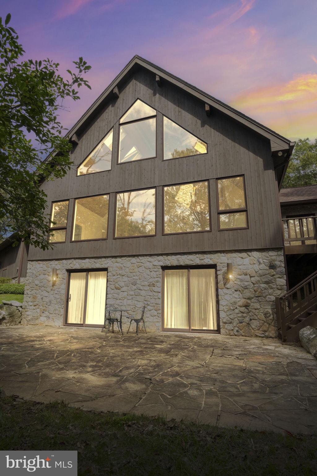 Nestled within the serene enclave of Laurelcrest, this exquisite chalet-style residence offers a blend of rustic charm and modern luxury. Set on an expansive 5.08-acre lot, the property is enveloped by lush trees and woods, creating a retreat like environment that feels worlds away from the hustle and bustle. As you step inside, you are greeted by an inviting open floor plan that seamlessly connects the living spaces. The heart of the home features a spacious family room, perfect for gatherings, adorned with a stunning double-sided wood fireplace that adds warmth and character. Skylights bathe the area in natural light, enhancing the inviting atmosphere. The gourmet kitchen is a culinary enthusiast's dream, boasting an island for casual dining, built-in cabinetry, including a single oven, dishwasher, and a convenient trash compactor. The main level also features a thoughtfully designed breakfast area, ideal for enjoying morning coffee while overlooking the picturesque surroundings. A walk-in shower in the rustic appointed bathrooms adds a touch of spa-like luxury, while the additional half bath ensures convenience for guests. Retreat to the upper level where four generously sized bedrooms await, each offering a peaceful sanctuary. The fully finished basement, with a rear entrance and walkout level, provides versatile space for recreation or relaxation, further enhancing the home's functionality. Outside, the property is complemented by charming exterior features, including exterior lighting options, a classic chimney, adding to its overall appeal. The side-entry attached garage provides ample parking and easy access. This residence is not just a home; it embodies an exclusive lifestyle, offering 24-hour security for peace of mind and the luxury of space to explore and enjoy nature. With additional parcels available, the possibilities for expansion or enhancement are endless. Experience the perfect blend of comfort, elegance, and natural beauty in this remarkable property, where every detail has been thoughtfully curated to create a warm and inviting atmosphere. Embrace the lifestyle you've always dreamed of in this stunning mountain retreat. This property could take on many forms: Home, family retreat, VROB, AirB&B