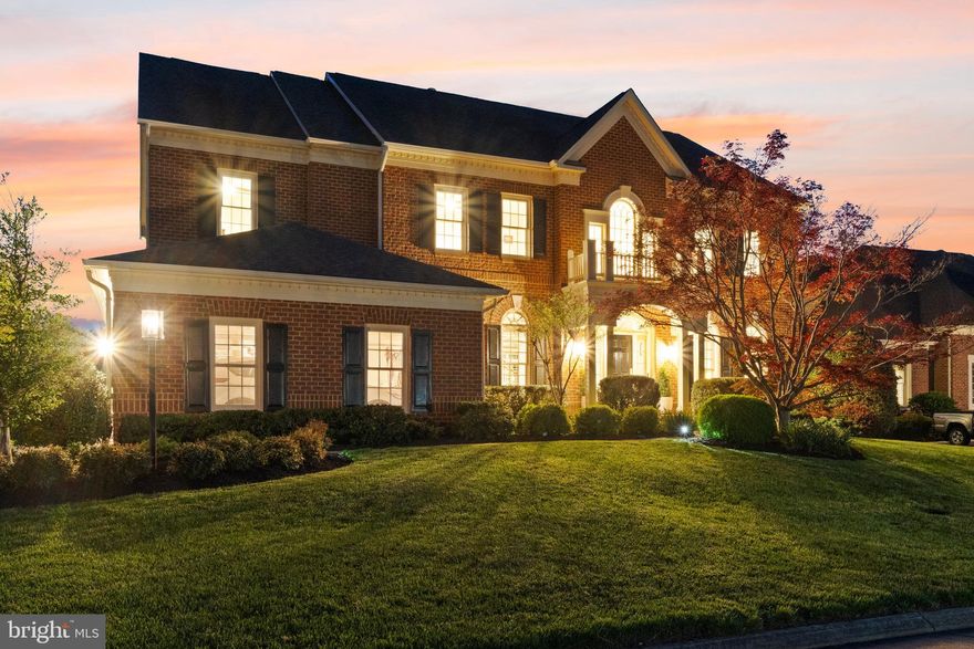 Experience exceptional living in this Contemporary Colonial estate located in the sought-after, guard-gated Lake Manassas community. Spanning over 6,500 sq ft of luxurious interiors, this home features two levels of outdoor living on a spacious 0.31-acre lot that backs to unobstructed water and golf course views, all perfectly positioned for stunning west-facing sunsets. Arrive on picturesque, tree-lined streets to the stately all-brick residence with a side-load three-car garage. A landscaped paver path leads to the covered front entry, welcoming you into a grand double-height foyer. Inside, formal living and dining areas are filled with natural light from a large Palladian window above, and sweeping stairs lead up to the bedroom level. The formal dining room pairs traditional wainscoting with contemporary lighting, and  hardwood floors flow throughout the main level. The renovated kitchen appears straight from a design book, featuring white Shaker cabinets, subway tile backsplash, granite countertops and island, and a suite of quality stainless appliances. Enjoy flexible dining at the island breakfast bar or the eat-in area surrounded by windows and views. The kitchen opens to a family room with coffered ceilings and a fireplace, and transitions seamlessly to the expansive deck for outdoor living and dining. Sunsets over the water provide a picturesque setting for your gatherings, both inside and out. Nearby, a dedicated office with built-ins and a bay window offers a quiet workspace, while the laundry/mudroom includes an upgraded LG washer and dryer and access to the garage.. Upstairs, a lofted space serves as a den or reading nook with built-in bookshelves and serene water views. Double doors reveal an impressive primary suite, complete with a coffee bar, private balcony, tray ceiling, and built-ins. The renovated closet functions as a luxurious dressing room with a marble island and chandelier, and the primary bath features an oversized soaking tub, double vanities, and a frameless shower for a spa-like experience. This level also includes a second bedroom suite with a walk-in closet and private full bath, plus two additional bedrooms connected by a jack-and-jill bath. The walk-out daylight basement offers additional living and entertaining space, including a rec room and French doors to the patio. The basement also features a fifth legal bedroom and fourth full bathroom, creating a tucked away private suite. Outdoor spaces include an upgraded deck and stone patio added in 2017, ideal for entertaining or relaxing while enjoying the golf course and pond views. Residents of Lake Manassas enjoy access to community amenities including an outdoor swimming pool, lighted tennis and basketball courts, tot lot playground, miles of walking and biking trails, parks, lake access for boating and fishing, and two championship golf courses. The location offers convenient proximity to major highways, highly rated Prince William County schools, and extensive shopping and dining at Virginia Gateway, The Shops at Stonewall, and more. All within 40 miles of Washington, D.C. and less than 25 miles from Dulles airport, providing a rare opportunity to enjoy the best of northern Virginia living in a truly exceptional setting.