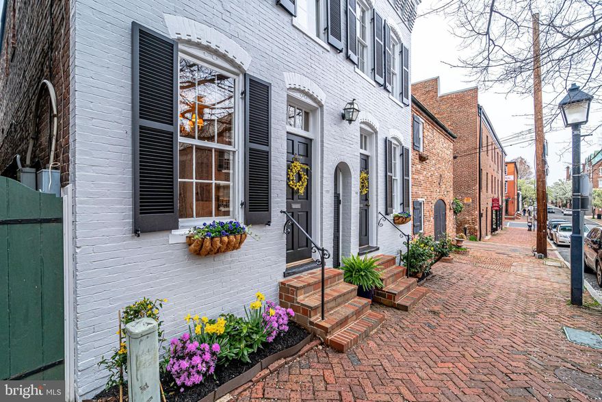 Live the Old Town dream mere feet from King Street!  Captivating, historic semi-detached, circa 1880 brick home, one-half block from King Street, one block to the Potomac River/Waterfront Park, in the desirable SE quadrant.  This rarely available, dramatic 25'-wide property was created from two separate homes (109 & 111) at the turn of this century.  It is "Everything Old Town" -- featuring a local artist's interior wall murals, 9' exposed beamed ceilings, original hardwood floors, 3 wood-burning fireplaces, an upgraded kitchen and cozy breakfast room with a  wood-burning fireplace, exposed brick and 9' beamed ceilings.       Enter through one of two front doors into a double front parlor, each with a wood-burning fireplace and beautiful original wood floors, into a fabulously open main level featuring two additional seating areas and an inviting dining room.  The upgraded kitchen features a Wolfe gas stove, cherry cabinets and granite counters (with an island for social seating) as well as an adjoining cozy fireplace and breakfast/sitting room.  From the kitchen French doors open to a roomy, private, stone-terraced landscaped courtyard & garden enhanced by  20-year-old indigenous  grape vines.       Returning inside, two separate staircases lead to a fabulous master bedroom & bath with a jacuzzi tub.  The unusually large master suite offers double walk-in closets and a morning sitting room where you can enjoy your coffee and online news before stepping out for a breath of fresh air on the private outdoor balcony overlooking the terraced garden.  Exposed brick walls and a unique wood-paneled inset, that fits a king size bed, highlight special features in a special room. Two sun-drenched, front, generously-proportioned bedrooms rooms, one with built-ins, and a full bath complete the second level.       An exciting Old Town lifestyle is at your fingertips as are dozens of outstanding King Street and waterfront restaurants, boutique shops, the free King Street Trolley, King Street Metro and an "only-one-block-away" Starbucks.  You won't have to drive in to enjoy the St. Patrick Day, President's Day or Christmas Walk Parades, you'll already have a front row location.  And not quite at you fingertips, but extremely close by are DC, the Pentagon, Reagan National Airport, George Washington Parkway/Bike Path,  MGM Grand and National Harbor and water taxis to Nationals Park .