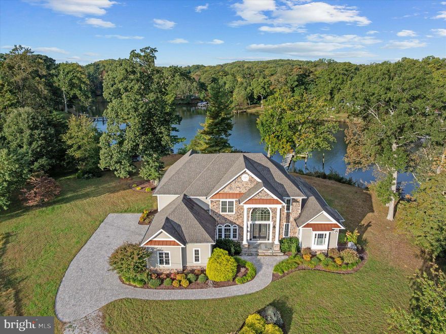 Welcome to 1576 Bay Head Road, a breathtaking custom-built waterfront estate on the peaceful Little Magothy River offering over an acre of privacy, 6,700 square feet of refined luxury, and direct access to the Chesapeake Bay in under five minutes. Built in 2017 and designed for modern living, this residence perfectly balances year-round comfort, elegance, and effortless waterfront enjoyment. Whether you’re hosting magical parties under the stars, intimate dinners by the fire, or grand holiday gatherings surrounded by family and friends, this home delivers the rare combination of sophistication, space, and setting that defines the Chesapeake lifestyle. The property’s rare level lot—not in a flood zone—makes waterfront living easy and practical, with a 60-foot private pier equipped with water, electric, and two deep-water slips ready for your boats, jet skis, and kayaks when the warmer days return. The location offers the best of both worlds: a protected, tranquil setting surrounded by mature trees, yet with open water just minutes away and no bridges to navigate. There’s so much potential here to expand, landscape, or design outdoor living spaces that match the home’s grandeur. Inside, the craftsmanship shines as sunlight pours through walls of glass, capturing sweeping river views from nearly every room. The chef’s kitchen features a six-burner gas range, quartz countertops, an oversized island, and professional-grade appliances, seamlessly flowing into the dining and living areas for effortless entertaining. The great room, anchored by a stone fireplace and dramatic double-height ceilings, is the heart of the home—ideal for cozy nights, celebrations, and making memories that last a lifetime. Expansive decks, including a covered porch and retractable awning, invite year-round outdoor enjoyment, from crisp fall mornings with coffee to spring afternoons overlooking the river. The main-level primary suite feels like a private sanctuary, complete with panoramic water views, balcony, and a spa-inspired bath. Upstairs, spacious bedrooms offer comfort and privacy for family and guests, while the fully finished lower level is an entertainer’s dream, featuring a theater room, wet bar, gym, office, and walk-out recreation space just steps from the water. Dual staircases, two fireplaces, and wide-plank hardwood floors elevate every detail of this exceptional home. Beyond its beauty, 1576 Bay Head Road is about lifestyle—peaceful, private, and perfectly positioned just minutes from downtown Annapolis and major commuter routes. It’s the ideal family compound, weekend escape, or event-ready retreat where every season brings its own magic. From enchanting dinner parties and waterfront soirées to cozy fireside evenings and summer days on the dock, this is a home designed to be lived in, celebrated, and loved year-round. 1576 Bay Head Road isn’t just a waterfront home—it’s a statement of timeless elegance, comfort, and possibility, where the best moments in life unfold effortlessly along the Chesapeake.