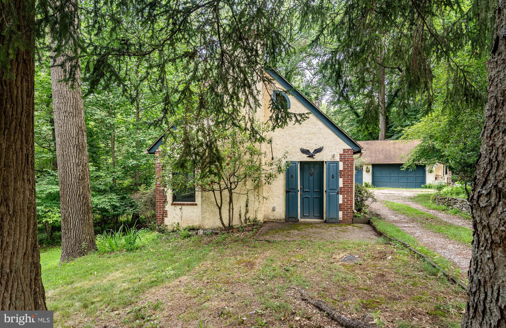 11 E Thomson Avenue feels more like a hidden cottage from a storybook than a typical Springfield home. Set back on a quiet lane and surrounded by mature trees, this Cape Cod welcomes you with its vine-covered exterior, moss-lined roof, and gravel drive leading to a two-car detached garage with electric.
Inside, rich wood tones, exposed brick, and beamed ceilings create warmth and texture. The living room centers around a cozy brick fireplace with a wood-burning insert, while the adjacent dining area features original wide-plank floors and a vintage chandelier. Brick columns frame the kitchen, adding character and a handmade quality that feels timeless.
Two first-floor bedrooms include a vaulted-ceiling space with sliding doors to a spacious deck—perfect for watching the leaves turn or listening to the creek below. Upstairs, two additional areas offer built-in drawers, sloped ceilings, and just enough quirk to feel magical.
The lower level includes a partially finished flex room, laundry, and storage, with walkout access to the fenced backyard. Step outside to find a multi-level deck, and a lush yard lined by trees and a gently running stream—a place that invites slow mornings and quiet evenings.
Recent updates include a new water heater (2023) and upgraded 200-amp electric. Additional features include stainless appliances, wall and window A/C units, public water and sewer, and plenty of off-street parking.
Located minutes from SEPTA, schools, shopping, and the Healthplex, this home offers an uncommon blend of charm, privacy, and proximity. It's not for everyone—but if you’ve ever wished for a home that feels like it could hold stories, you’ll want to see this one.