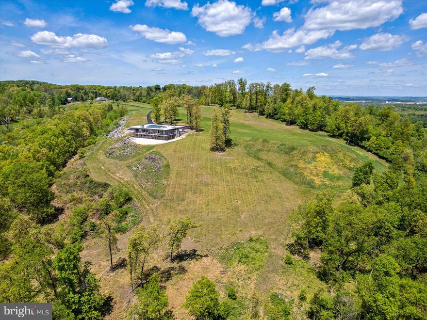 Sitting on 29 plus acres in Bern Township, Berks County, stands this one-of-a-kind contemporary home boasting five bedrooms, five full baths, and over 8,200 square feet of living space. With a new, private driveway, improvements to the deck, new garage door, and many other recent improvements, this fabulous property is ready to go! Throughout you will find amazing modern design and delightful features, including exposed stone walls, angled wood ceilings, exposed beams, and so much more. The panoramic views can be enjoyed from most windows and especially from the wraparound covered deck. One of many highlights is the centralized heated concrete indoor pool. It can be accessed from many areas of the home, and as you look up, you will be amazed by the vaulted glass ceiling overhead. It allows lots of bright sunlight in or even enjoy a night swim while looking up at the stars. Take advantage of convenient first floor living with an owner's suite that has amazing views, deck access, and a wood ceiling. The owner's private bath features a shower with steps down to a tiled bath. A floor to ceiling stone wood burning fireplace offers another area for entertaining or relaxing and also accesses the pool or the deck with views. The open kitchen has lots of cabinet and counter space, stainless steel appliances, exposed beams, and angled wood ceilings. Also on the main floor are two other spacious bedrooms, each with its own private full bath. The finished walkout lower level offers endless possibilities with two bedrooms, two full baths, exposed stone walls, floor to ceiling windows that allow abundant natural light, and additional fabulous views. The lower level provides another great spot for bringing together family and friends or provides a private place for guests and in-laws to stay. Do not miss this unique home with spectacular views. Schedule your showing today!