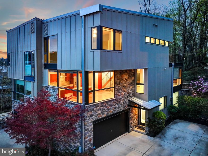 Welcome to Overlook at Clipper Mill.  A unique and contemporary enclave in Baltimore City built to LEED Silver standards.  Surrounded by the 745 acre Druid Hill Park, this is one of the most stunning neighborhoods in all of Baltimore.  Natural light pours in through the walls of windows.  3411 Woodberry Ave is tucked away in the rear of the community and backs directly to woods with access to walking and biking trails.  This is the larger and more sought after model, featuring almost 3000 square feet of finished living space and a two car garage.  The recently renovated first floor includes a flexible space that could be used as a bedroom / office / studio / or almost anything you could imagine, plus a custom walk-in California Closet, a full bathroom, a Flare fireplace, and stunning epoxy concrete floor.   On the main level of the home you will find an open concept design flooded with light and gorgeous views.  The kitchen has a large island and Bosch appliances.  A gas fireplace in the living room / dining room create an added elegance, and the sun room overlooks the beautiful park.  The upstairs is complete with two generously sized bedrooms, two bathrooms, and a laundry room.  The primary suite includes a walk-in closet, and a bathroom featuring separate shower and tub with a ceiling-mount bath filer further enhancing the modern aesthetic.  The rear exterior of the home features two IPE decks, a permanent gas line for a grill, a patio, and grassy yard.  Plus access to what is widely considered the coolest pool in Baltimore.  There really is no other community and house quite like 3411 Woodberry Ave.