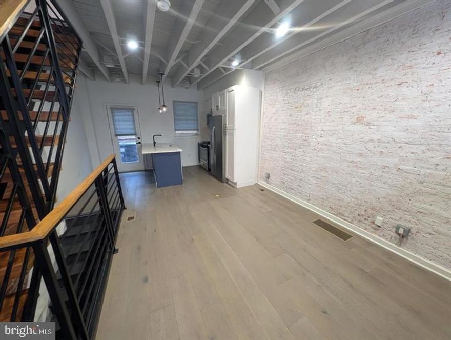 Rent is $2600/month for a 2-year lease & only *$2700/month* for a 1-year lease. Perfect for a family or 2-4 roommates! Gorgeous, recently built townhouse, conveniently located just 2 blocks from the Market-Frankford (MFL) train line and steps away from local businesses, restaurants, and bars. Thoughtfully designed 3 bedroom, 3 bath home with a bonus room in the basement that can be used as a 4th bedroom. Enter into an open floor plan with exposed brick & wood ceiling joists, adding height to the space. Tap into your inner chef with this luxury-grade kitchen featuring stainless steel appliances, white shaker cabinets, and an island with bar seating. Continue back through the glass door which leads you to a back patio, perfect for grilling or outdoor entertaining. The 2nd-floor hosts 2 spacious bedrooms and a full bathroom. The 3rd floor is your primary suite oasis, complete with a balcony, exposed wood beams, full bathroom, and walk-in closet. The roof deck has wonderful city views and is a great place to gather outdoors. Rounding up this home is a fully finished basement which can be used as an additional bedroom, gym, or home office. Conveniently located on this lower level is laundry and another full bathroom, making it a perfect guest suite.