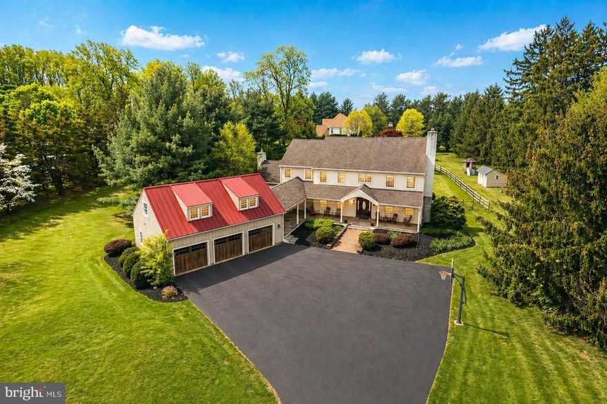 This one hits different from the start. Set back on 2.3 acres behind a stone wall and mature trees, there’s a sense of arrival before you even hit the front porch. A covered porch runs into a breezeway that links the house to an oversized three-car garage, with a flagstone patio tying it all together. The look leans farmhouse, but the red standing seam metal roof over the garage gives it a sharp, custom edge. Out back, a paver patio leads to a private, fenced yard and a pool that feels tucked away on its own little island, surrounded by a generous concrete patio encircled by evergreens. The pool was completely renovated just 3 years ago, including a full gunite replacement, new coping, pumps, and filtration system. Step inside to nearly 6,000 square feet of finished living space, five bedrooms, and 3.5 baths. The entry makes an impression right away with rich flooring and a staircase that makes a statement the second you walk in. To one side, a proper study. To the other, a living room with a gas fireplace and tall windows that pull in light all day. A pocket door leads to a dining room just off the kitchen, easy to use. Right in the middle of it all is the kitchen. Big island, gas cooking, high-end appliances, and plenty of cabinet space. It opens directly into the family room, where the ceilings climb, the beams show off, and windows wrap the space in natural light. A second gas fireplace anchors the space. And then there’s the sunroom. A full rotunda-style space with a curved metal roof overhead and a wood ceiling and exposed beams that add real character. It steps right out to the patio. Going up the staircase, you arrive at a wide landing with built-ins and a clear view of the backyard, then it opens to four spacious bedrooms and three full baths. The primary suite features a vaulted ceiling, a true sitting area, a walk-in closet with built-ins, and a well-finished bathroom with a double vanity, soaking tub, and tiled shower with a frameless glass door. A finished third level that can flex however you need; bedroom, office, gym, you name it. There is a separate mini split for this area for heating and cooling. A partially finished basement extends the living space and also has plenty of unfinished space for storage. And that garage, heated, oversized, and topped with an unfinished area that’s ready whenever you are. It’s private without being isolated, spacious without feeling excessive, and it simply feels right.