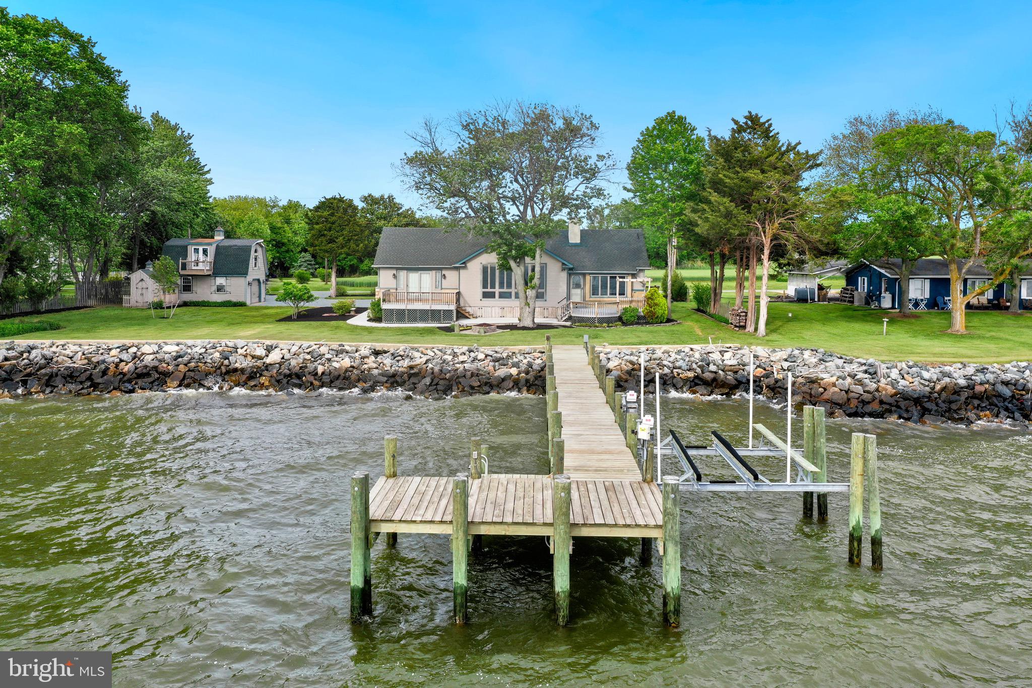 Nestled on .83 acres, this captivating Chesapeake Bay waterfront home offers the perfect blend of comfort and coastal charm just outside of Rock Hall. The property includes a 3-bedroom plus bonus room, 2 1/2-bath main house and a detached garage with a 1-bedroom, 1-bath efficiency apartment, ideal for guests or potential rental use. Step inside to be welcomed by a stunning wall of windows showcasing panoramic views of the Chesapeake Bay. The spacious family room features vaulted ceilings and a cozy wood-burning fireplace, creating an inviting space for relaxation. The modern, coastal kitchen is a chef’s delight, boasting a large island, a breakfast area, and new appliances. The bayside primary bedroom is a serene retreat, complete with sliding door access to a deck, an en-suite bathroom, and an oversized closet. Two additional guest bedrooms on the main level share a full bathroom, providing ample space for family or visitors. Upstairs, a versatile bonus bedroom with a half bath offers flexibility for various needs. The expansive laundry room comes equipped with an additional refrigerator, wine refrigerator, sink, and plenty of storage space. The efficiency apartment above the detached garage provides privacy for guests, featuring a full bathroom and a balcony overlooking the picturesque bay. Outdoor living is at its finest with two waterside decks, a picnic area, and a fire pit perfect for gatherings. The new pier with a 10,000 lb boat lift makes boating and water activities a breeze. Watch breathtaking sunsets over the Chesapeake Bay and create lasting memories in this home designed for entertaining family and friends. Don’t miss the opportunity to own this extraordinary waterfront retreat—schedule your private viewing today!