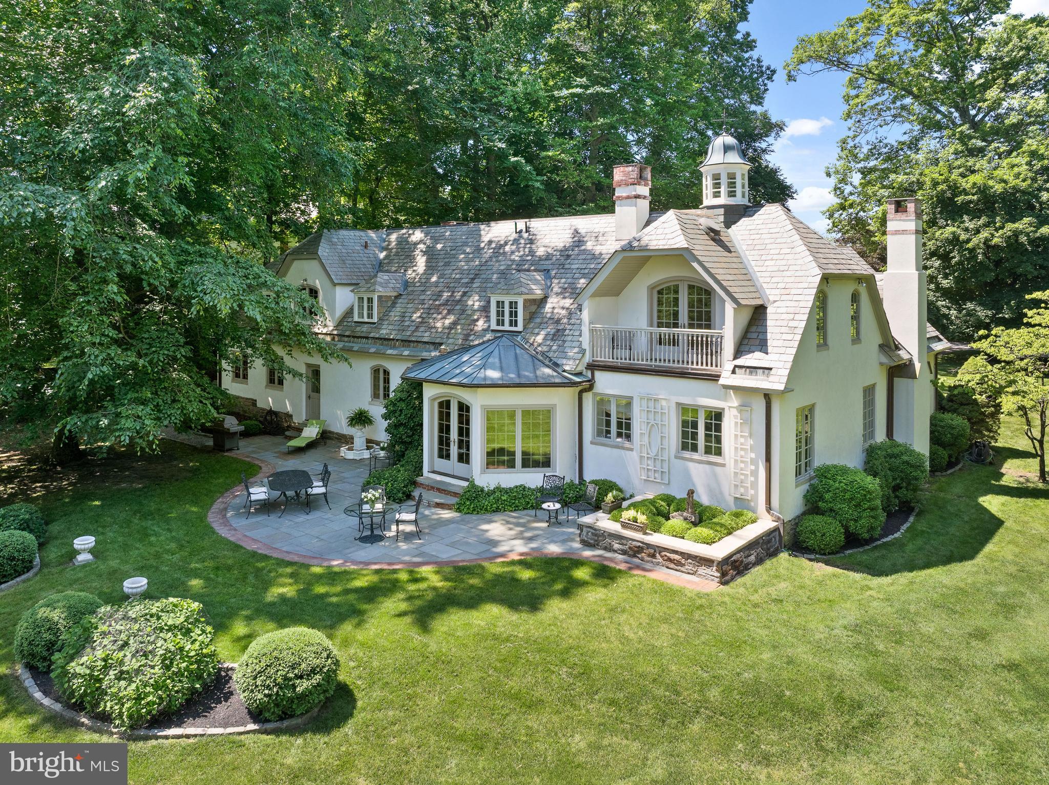 Welcome to 599 Longchamps Drive, a one-of-a-kind architectural masterpiece nestled in the heart of the Main Line, within coveted Radnor Township. Your heart is captured from the moment you see the breathtaking cupola with its custom weather vane, and pitched slate roof, accented by copper gutters—a trio of timeless details that set the tone for the beauty that lies within. Originally the carriage house for the famed D'Orsay estate, this enchanting residence was completely transformed by its current owners in 1995, beginning with a stone foundation and terra cotta block under the stucco. Every inch of this picture-perfect gem has been curated with the finest quality and craftsmanship, all while preserving the timeless charm and soul of its historic roots. Perfectly sited on a stunning 1-acre lot, from the moment you arrive, you’ll feel as though you've been transported to the South of France. Upon opening the front door, an air of sophisticated elegance abounds as gleaming walnut floors welcome you into the two-story Foyer. Featuring a custom walnut staircase, intricate millwork, and detailed crown moldings, the Foyer introduces the elevated design and seamless, natural circular flow that continues throughout the First Floor. The elegant Living Room, anchored by a stunning fireplace flanked by custom display cabinetry, exudes warmth and refinement, while a private Office offers a quiet retreat. The inviting Family Room is a sunlit sanctuary, featuring bay casement windows and elongated elliptical French doors that open to a slate Patio framed by manicured boxwood gardens—creating the perfect balance of beauty, privacy, and indoor-outdoor living. At the heart of the home lies a European-inspired gourmet Kitchen, complete with high-end appliances, marble countertops, and views into the Dining Room, overlooking a gas fireplace and picturesque ivy-covered brick courtyard. The Dining Area opens directly to this private courtyard—perfect for seamless entertaining and al fresco dining in a truly enchanting setting. A convenient first-floor Laundry/Mudroom and an attached two-car Garage add to the home’s effortless livability. Ascend the sweeping staircase in the Foyer to find an exquisite Primary Suite, where elegance and serenity converge. The suite features a tray ceiling, its own fireplace, and a unique architectural view into the home’s cupola. French doors lead to a private balcony overlooking the lush, flat backyard. The suite also includes his and her walk-in closets and a luxurious en-suite Bath featuring limestone floors and marble countertops. Three additional Bedrooms—each with unique dormers and charming window seats—share an updated Hall Bath, offering warmth, character, and comfort for family or guests. An unfinished Lower Level provides abundant storage space, with the exciting potential to finish and expand the home’s living area to suit your needs and lifestyle. Outside, the backyard is a private haven, featuring a spectacular Patio framed by mature landscaping—ideal for hosting, relaxing, and making cherished memories. This is more than a home; it is a rare and remarkable lifestyle opportunity. Come experience the magic of 599 Longchamps Drive—where Old World charm meets modern elegance in the sought after D'Orsay neighborhood. SHOWINGS BEGIN THURSDAY APRIL 3rd