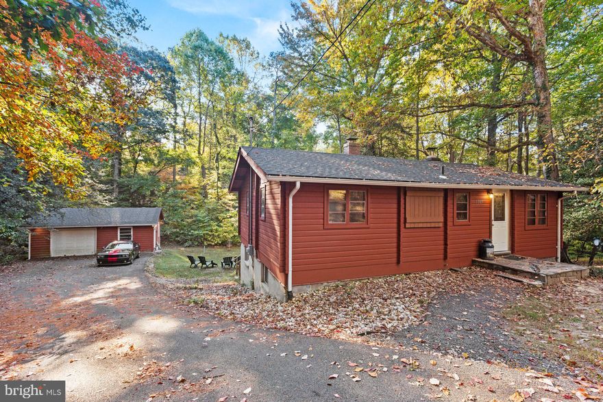 Come join us and tour this  OPEN HOUSE - SATURDAY, 16 NOV  11:00 A.M. - 1:00 P.M. 
PRICED REDUCED - Live in your own peaceful oasis surrounded by nature.   Keep snug and cozy while sitting around the fireplace in this rustic 2 bedroom, 2 bath log cabin built with rich wood. Enjoy brisk evenings sitting on the deck off of the living room. Seller willing to provide concessions for floor refinishing. The unfinished basement has a laundry room and full bath and is entered from the outside.  The basement has endless possibilities; there's plenty of room for storage, can be turned into a mancave/craft room, or even a guest room.  The detached garage is amazing with tons of work space, electricity,  room to work on cars, and room to store lawn equipment.  HVAC replaced in 2021. New kitchen appliances were purchased in 2022, along with new plumbing in the kitchen. Roof replaced on garage in 2023, and roof on house replaced in 2024. Driveway paved in 2023.  Key in lockbox fits house, basement, and garage.