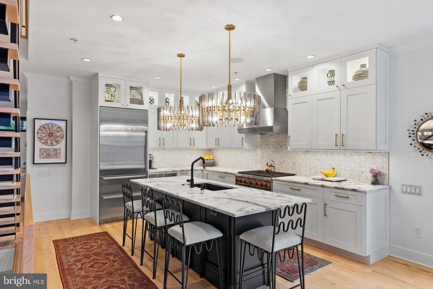 741 Bainbridge, in the heart of Queen Village/Bella Vista, is a 3,500 square foot, end of row townhouse offering 3 sides of light, oversized garage parking, and sophisticated urban living throughout.

Whether entering the home from the front door or garage, you are welcomed with beautiful maple hardwood floors (throughout) and with immediate access to a coat closet. The entry hall leads you into the heart of your open plan living space where the kitchen, dining, and living room flow together and where double doors lead to your garden and outdoor grilling area. The kitchen features a flexible, extended and chandeliered kitchen island, top chef grade appliances, Oyster white marble counters and mosaic style marble backsplash. You are quickly invited into the warm and finely detailed living room in which the fireplace is surrounded by elevated Cristallo Quartzite (stone), sourced from Brazil. The walnut mantle is flanked with custom adjustable walnut millwork for displaying treasured items and with lower tambour doors for added texture, storage, and sophistication.

The 2nd level brings you to two large secondary ensuite bedrooms with generous closet space separated by a large and convenient laundry room.

The 3rd level brings you to your flexible primary suite floor with its own private balcony, basket weave marble tiled ensuite bathroom, and two large walk-in closets. At the top of the steps is a custom designed office which could easily serve as a nursery or bedroom.

Atop is your stunning rooftop deck with unobstructed views of the city. The rooftop is outfitted with outdoor seating, gas firepit, custom planters, specimen plantings and automated irrigation that extends to the planted front window boxes.

The lower level is a relaxed family and entertaining space with a full bath and wet bar which could serve as a fourth bedroom. The second room serves as a project area outfitted with cabinetry for your tools, projects and has a large storage area.

And finally, you are in the coveted Meredith school catchment. Welcome to 741 Bainbridge.