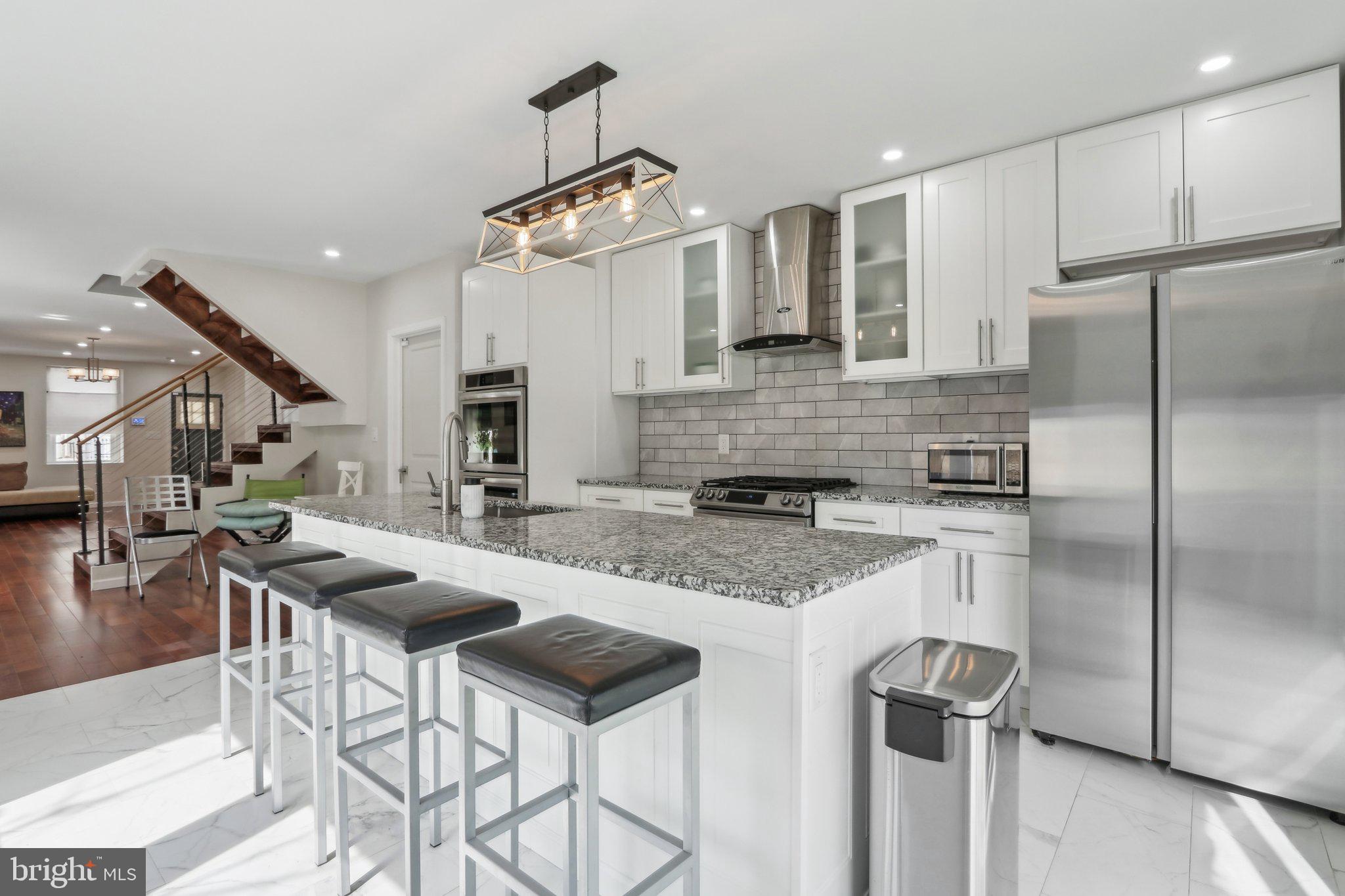 Welcome to this beautifully renovated, nearly new construction end-of-row home. This home rests on a quiet block with only local traffic in the highly desirable neighborhood of Manayunk, a superior vantage point offering panoramic views overlooking the city skyline and western suburbs. With eight years remaining on the tax abatement, this home was meticulously rebuilt, keeping the front and side walls, offering modern living while maintaining the charm of the area. As you enter, you are greeted by a spacious, open-concept main level with gleaming hardwood floors. The living room flows effortlessly into the dining room, which then leads into a chef’s dream kitchen. This kitchen features crisp white tiled floors, an oversized center island with seating, granite countertops, stainless steel appliances, a double wall oven, and a gas range, making it perfect for everyday cooking and entertaining. Sliding doors open to a serene, shaded rear deck with access to the front of the home through a private walkway, providing a peaceful outdoor space. The second level features two enormous bedrooms, each with hardwood floors, and one with a Juliette balcony, offering ample space and natural light. These bedrooms share a full hall bathroom with a tiled tub/shower combo. Conveniently, the laundry room is also located on this level, making chores a breeze. On the third level, you’ll discover two more generously sized bedrooms, both with hardwood floors and Juliette balconies, including the grand primary suite. This sanctuary boasts two walls of windows that flood the room with light, a spacious walk-in closet, and a luxurious ensuite bathroom with a dual vanity and a seamless walk-in shower. The second bedroom on this level is also large and is serviced by a full hall bathroom featuring a soaking tub and a stall shower. The home’s crowning feature is the rooftop terrace with stunning views of the Schuylkill River, offering a serene retreat to enjoy morning sunrises or evening sunsets. The partially finished basement is perfect for additional storage or can easily be transformed into additional living space to suit your needs. Luxury features include dual-zone climate controls with two central air cooling systems, a French Mansard-style roof, and original 12-inch-thick walls that ensure energy-efficient temperature control and a quiet, private haven. Located just blocks from the vibrant Pretzel Park, the bustling shops, cafes, restaurants, and bars of Main Street in downtown Manayunk, several supermarkets, a SEPTA regional train station, and close to the Schuylkill River Trail spanning 30+ miles from Center City to Valley Forge National Park, this home places you right in the heart of everything the neighborhood has to offer. Don’t miss your opportunity to make this stunning property your own!