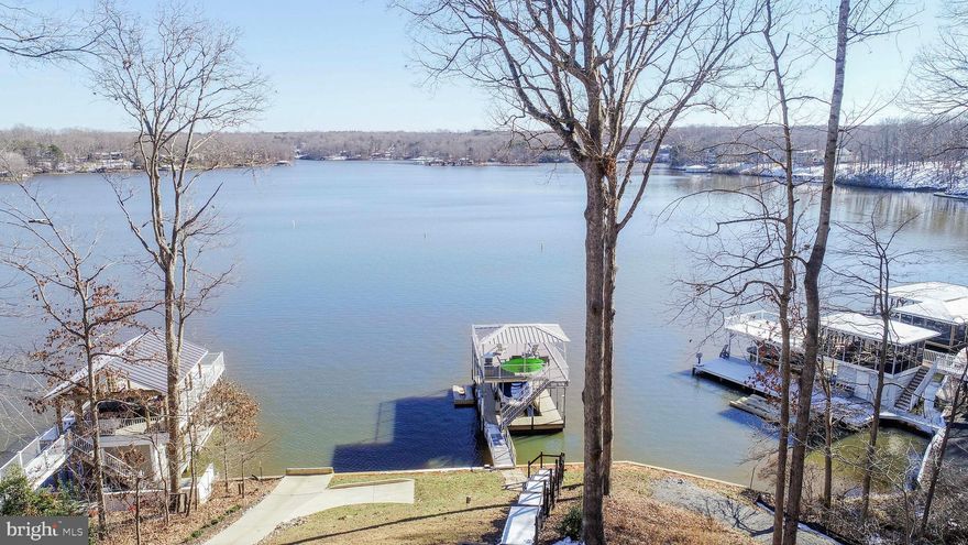 Check out the views from this home!  Completely remodeled, this stunning 5 bedroom, 3 bath home offers 3 finished levels of living space.  Open floor plan with large windows and views of the lake from almost every room of the house.  The Great Room has a stone fireplace, built in entertainment center and hardwood floors.   The kitchen has been remodeled with granite counter tops, stainless steel appliances and LVP flooring.   Dining area with hardwood floors and room for a table of 10 as well as extra seating at the breakfast bar.   There are two large bedrooms and a full bath also on the main level.  Upstairs is a very generous en suite with breathtaking views of the lake.  The attached full bath has a double vanity and an oversized walk in shower.  There is a second bedroom on this level as well and a walk in attic area.  The full finished walk out basement is open and bright with a large rec room area, another bedroom and a full bath.  There is additional storage as well.   Outdoor entertaining options include a large deck, screened in porch and covered patio area.  New floating dock with electric lift and upper deck.  This property  is located in a no wake zone of a protected cove with super deep water--18+ feet!  New exterior doors,  new deck, new carpet in the bedrooms and the kitchen & bathrooms have been completely remodeled.   Whole house generator, water filtration system, paved driveway, storage shed and circular driveway for golf cart to the water are additional perks of the home.    Gated community with HIGH SPEED FIBER INTERNET and short term rentals are allowed.   Good central location on the public side of the lake located just a  short distance by land or by water to local restaurants.  Home shows like new!