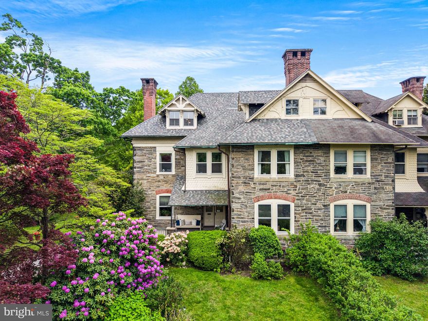 Situated on one of East Mt. Airy’s most picturesque and sought-after blocks, 312 E. Gowen Avenue is a rare and beautifully preserved Frank Furness stone twin. Originally part of the renowned Gowen Estate established in the 1880’s, this home offers timeless architecture, gracious living spaces, and extraordinary gardens on over half an acre. Rich in character and architectural detail, this exceptional 5-bedroom, 2 full baths, 1 powder room residence seamlessly blends historic craftsmanship with modern livability in one of Philadelphia’s most beloved neighborhoods. First time offered in over 60 years, this is a truly special opportunity to own a cherished home with remarkable history and preservation. Set back from the street behind mature trees and sweeping lawns, the home’s striking Wissahickon schist façade, steep gables, deep covered front porch, and oversized chimney create a storybook presence with undeniable curb appeal. The expansive porch overlooks thoughtfully cultivated gardens and lush seasonal plantings, offering a peaceful setting for relaxing among the blooms. Inside, sun-filled formal living and dining rooms showcase remarkable original woodworking, rich hardwood flooring, oversized windows, crown moldings, picture rails, built-ins, and woodburning fireplaces. A spacious first-floor study/library with custom built-ins and an additional woodburning fireplace provides the perfect work-from-home retreat, reading room, or den. At the heart of the home is a large eat-in kitchen with center island, abundant cabinetry, and direct access to a beautifully restored gardening shed and rear grounds. A secondary staircase off the kitchen leads to a private upper-level bedroom, ideal for guests, studio space, or an additional office. The second floor features two additional generously sized bedrooms and a spacious primary suite with a wood burning fireplace and an adjoining sitting room/home office en suite, offering endless opportunities to create a dressing room, reading lounge, or work-from-home space. The third floor offers an additional bedroom, a full bath/laundry space, and a large rec room/playroom with treetop views, providing flexible living space for guests. Throughout the home, original wood trim, solid doors, deep windowsills, and historic detailing create an atmosphere of warmth, elegance, and authenticity. Outside, the property continues to impress with mature landscaping, extensive gardens, and a large private driveway offering ample parking. The location is exceptional and just steps from the Mt. Airy train station for an easy commute to Center City, and moments from the shops, cafés, and restaurants along Germantown Avenue. Nature lovers will appreciate the close proximity to Fairmount Park and the Wissahickon trails. This is a rare opportunity to own an architecturally significant property within the Gowen Estate story.