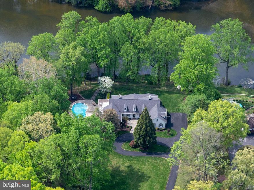 Tucked away on a quiet cul-de-sac in Potomac’s coveted Great Falls Estates, this beautifully renovated custom residence pairs sophisticated design with true outdoor living set on over two acres. Surrounded by mature trees, rolling lawns and abutting a 9 plus acre private lake, the home offers privacy, yet is just moments from Potomac Village. Walk from the back yard to hiking paths leading into Great Falls National Park. Easy access to both Reagan National and Dulles International airports.
Step through the front doors into a light-filled foyer that opens to expansive formal and casual living spaces, all unified by warm hardwood floors, high ceilings and a fresh designer palette. An inviting living room with classic fireplace and large-scale windows flows seamlessly to the dining room, creating a gracious backdrop for both intimate evenings and large-scale entertaining. Floor to ceiling full room width glass panel doors fold to open up the living space from the dining room to the porch. The kitchen features double ovens, double sinks, induction cook top and oversized side-by-side refrigerator and freezer along with a walk-in pantry. Side door covered mud room entrance leads into the kitchen. The main level features a primary bedroom suite with updated bathroom with soaking tub and separate shower. The suite includes in-home office, and sunroom overlooking the lake. 
The upper-level features four amply sized bedrooms, with gleaming hardwood floors, tranquil treetop and lake views and two Jack-and-Jill bathrooms. Also on this level is a large bonus flex room and a second washer and dryer. A sixth bedroom is accessed by private staircase which leads to a charming dormered bedroom and full bath, providing privacy for family, guests or an au pair. 
Designed for how people live today, this home utilizes geothermal heating and cooling. The home’s layout offers multiple places to work and study. On the lower level, an airy family room, high ceilings, built-in shelving, and direct walkout access to the pool terrace. It’s ideal for game nights, or movie marathons. A dedicated wet bar with seating, wine cooler and ice maker allows for casual entertaining. Two full baths allow his and her changing rooms for the pool. An additional room allows for a home gym with space for strength and cardio equipment keeps wellness conveniently close to home. Utility room has staircase access to mudroom and also staircase to side yard. 
The private lake can be used for fishing and kayaking.  NO motorized boats.