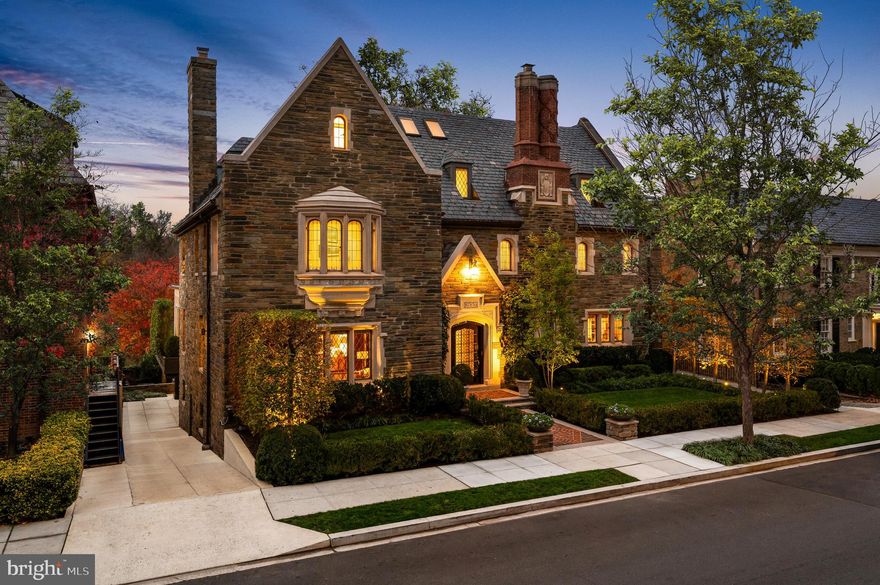 Just off Embassy Row, tucked in the heart of Washington’s distinguished Kalorama neighborhood—home to diplomats and socialites—stands 2435 Kalorama Road NW, a breathtaking 1928 English Manor. Once the residence of the Ambassador to Denmark, this home showcases extraordinary craftsmanship and architectural details from a bygone era.

Set on a quiet, verdant street, manicured hedges frame an intricate brick walkway traversing double lawns to the main entrance, which is adorned with a hand-carved limestone surround and full stone façade. Tudor-style windows and a towering, embossed double chimney stack punctuate the slate roof, exuding historic charm.

Inside, the reception area boasts Venetian plaster walls, limestone flooring, and intricately restored plaster molding. A curved mahogany staircase spirals upwards, bathed in natural light from a skylight above, serving as a functional work of art. Through double French doors lies the library, with built-ins and a shallow cathedral ceiling.

The formal living room spans over 30 feet, highlighted by a gas fireplace with an original hand-carved stone surround, while accent lighting enhances the space. Beyond, a sunroom designed by Ankie Barnes of BarnesVance Architects brings a contemporary flair with floor-to-ceiling windows and a glass cathedral ceiling fitted with automated blinds, creating an ethereal space overlooking the rear grounds. The formal dining room, banquet-sized for grand entertaining, features an original wood-burning fireplace, restored plaster molding, and recessed starlight lighting. Adjacent is a more intimate family room with hand-painted walls and a morning room with French doors opening to the rear deck. The chef’s kitchen blends modernity and function with sleek stacked cabinets, granite countertops, and top-of-the-line appliances, including a Wolf range, a commercial Traulsen double refrigerator, and quadruple SubZero freezer drawers.

The upper level is anchored by the sumptuous primary suite. Entered via a private sitting room, it includes a fireplace, a private office with expansive views, two large walk-in closets with built-ins, a mirrored dressing room, and a marble-clad ensuite bath featuring double vanities, a soaking tub, a walk-in shower, and twin water closets. Additional upper-level highlights include a second bedroom with an ensuite bath, a walk-in cedar closet, and elevator access.

The top floor offers a large third bedroom with a dressing area and ensuite bath, as well as a fourth bedroom featuring a beamed ceiling, wet bar, and private office with National Cathedral views. A Jack-and-Jill bath connects the latter to a bonus room, currently used as a fitness center.

The lower level provides a fully self-sufficient in-law suite with a dedicated entrance, a mudroom, laundry facilities, and access to the attached three-car garage and additional carport. A spacious recreation room opens to an expansive patio with brick pavers and a fire pit, all enclosed for ultimate privacy.

State-of-the-art systems include a sophisticated HVAC, DCS and Crimpco security with exterior cameras, and a comprehensive Lutron system controlling whole-house lighting and audio.

With its distinguished location, impeccable craftsmanship, and modern amenities, 2435 Kalorama Road NW is a masterpiece of timeless luxury and one of Washington’s finest offerings.