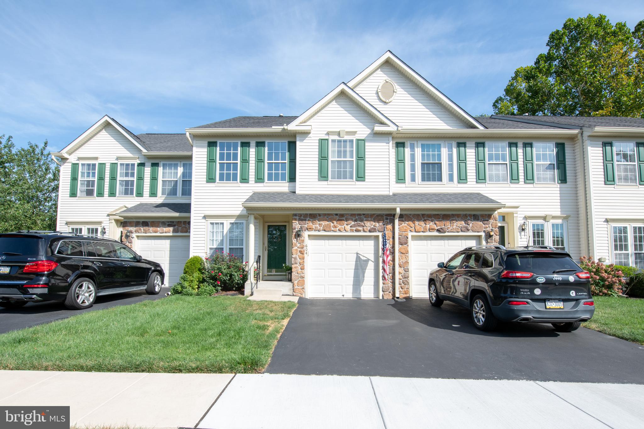 This sun-filled townhome blends thoughtful updates with easy living. A stone-accented exterior, covered entry, and an attached garage set a welcoming tone. Step inside to warm wood floors, crown molding, and custom trim that carry through the main level. The living room rises with a dramatic vaulted ceiling and a balcony overlook adds an open, airy feel while recessed niches offer display space for art and décor.
The kitchen is bright and efficient with white cabinetry, stainless steel appliances, and a tile backsplash. Prep space and storage are plentiful, and the adjoining dining area sits by a large slider for natural light and quick access to the deck. The first-floor main bedroom is a calm retreat with soft paint tones, crown molding, and a ceiling fan. It connects to a private full bath and keeps day-to-day life on one convenient level. A powder room and laundry nearby add function without fuss.
Upstairs, two comfortable bedrooms share a full hall bath. The open landing overlooks the living room and works well as a reading nook or a small desk area. Need more room to spread out? The finished lower level answers with wide-open space, luxury vinyl plank flooring, recessed lighting, and another powder room—great for movie nights, hobbies, or workouts, with storage tucked out of sight.
Outdoor time is easy on the maintenance free deck with a retractable awning, and plantings that provide shade & privacy.
Location seals the deal. From this quiet street you’re minutes to shopping, dining, parks, and major routes for smooth commuting. The home has been cared for with an eye for detail, and it shows in every room. Come see how comfortable, stylish, and practical life can be at 604 Tulip Drive—then plan your next steps.