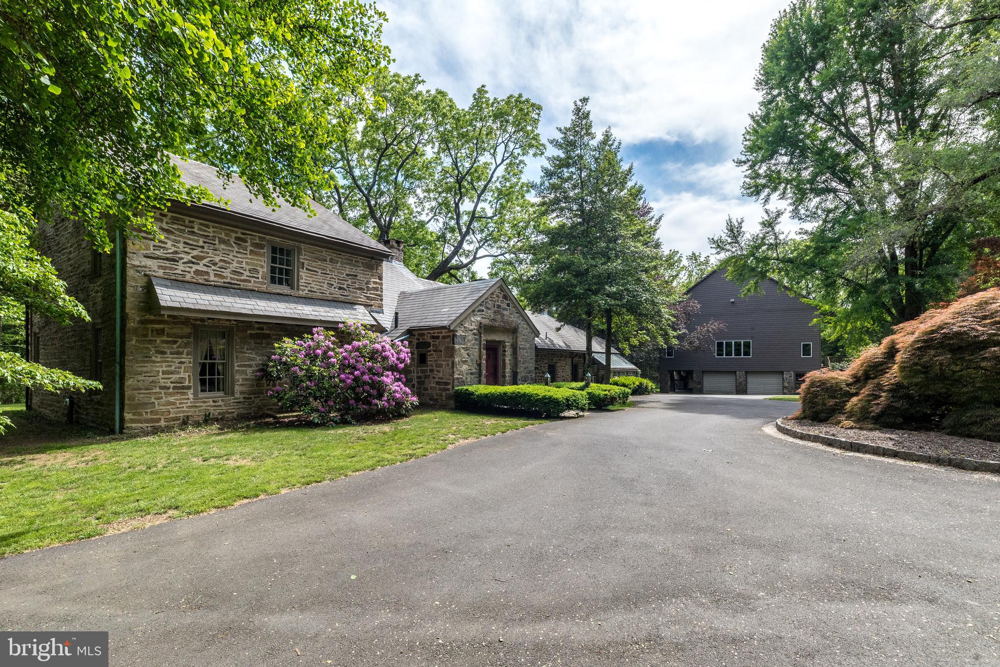 Step into a world where timeless elegance meets European charm as you enter this extraordinary 4 Bedroom, 2.5 Bath stone estate with over 4000 sq ft, built in the 1800s and thoughtfully updated over the years, evoking the enchanting feel of a cottage nestled in the English countryside, accompanied by a 4500 sq ft updated Bank Barn w/finished space & abundant storage. Beautifully situated and hidden from the road, down a long, tree-lined driveway (1 of 2 entrances), on over 3 secluded, fully fenced acres in North Wales, this property also enjoys being part of the neighborhood of Montgomery Lea, with a 2nd gated entrance within the cul-de-sac of Major Dr. This exciting home is constructed entirely of solid stone, with a slate roof & has masterfully preserved its rich historic character, w/reclaimed wood beams & hardwood floors throughout. The thick stone walls, original details, & hand-crafted finishes create a warm, storied atmosphere that is both romantic and enduring. Inside, every room tells a story, offering inviting spaces with panoramic views of the surrounding landscape. Whether enjoying a fireside evening or a sun-drenched breakfast nook, the home’s charm is palpable in every corner. The entrance foyer features a custom Butler’s Pantry and leads to an inviting Family Room w/stone floor, walk-in gas fireplace, exposed beams, & 2 sets of French doors leading to the 1st of 2 Patios overlooking luscious rear grounds. A 2nd set of French doors opens to the extremely spacious Living Room w/exposed beams, wide plank hardwood floors, 2nd walk-in gas fireplace & included hutches. A stunning stone wall w/arched opening leads from the Family Room to the lovely Dining Room with a gas stove sitting within a stone niche, wood ceiling w/exposed beams, & included custom table & chairs. The enchanting, updated country kitchen features a tiled floor, peninsula w/maple counter, cabinets constructed from reclaimed barn wood, newer double Viking stainless wall ovens, tiled backsplash, stainless dishwasher, electric stove w/griddle, & walk-in pantry closet. A full wall of windows adds warmth & a panoramic view of the rear grounds. Relax or entertain in the adjacent sun room w/walls of windows, a vaulted ceiling w/glass panels & a built-in bar w/gas stove & quartz counter. A French door from this room leads to the 2nd exterior Patio. The 2nd floor features a spacious Master Ste with 4th fireplace in the Bedroom, Dressing Room w/new carpet and multiple walk-in closets, and totally updated Full Bath w/vanity w/marble counter & stall shower w/frameless glass door. 2 Additional Bedrooms plus a renovated Hall bath & the Laundry Rm w/included washer & dryer complete the 2nd floor. The 4th Bedroom with new carpet is located on the 3rd Floor. An unfinished basement includes Central Vac, a water softener, gas furnace, Bilco doors, & radon remediation system, plus there is a hookup available to connect to public water. Enjoy the outdoors on the 2 inviting flagstone patios overlooking the lushly landscaped grounds featuring specimen trees & shrubs, a wishing well & delightful tree house. Adding even more appeal is a stunning 4,590 sq.ft. bank barn, thoughtfully restored to complement the main residence, including brand new siding. Within the barn, you’ll find 1360 sq ft of finished living space complete with a large gym w/included universal & weights. This spectacular space is ideal for guests, hobbies, creative space, or even a private office & includes 3 floors of unfinished space w/unlimited potential including workshops, storage & more. The lower level offers a 4-Car Garage, & a covered stone portico overlooking the manicured grounds. The panoramic views of nature and the property’s seclusion offer the tranquility of a countryside retreat and yet the benefits of being a part of a neighborhood. With its storybook architecture, rich materials, & lush surroundings, this one-of-a kind property is a true blend of history, luxury, and charm.