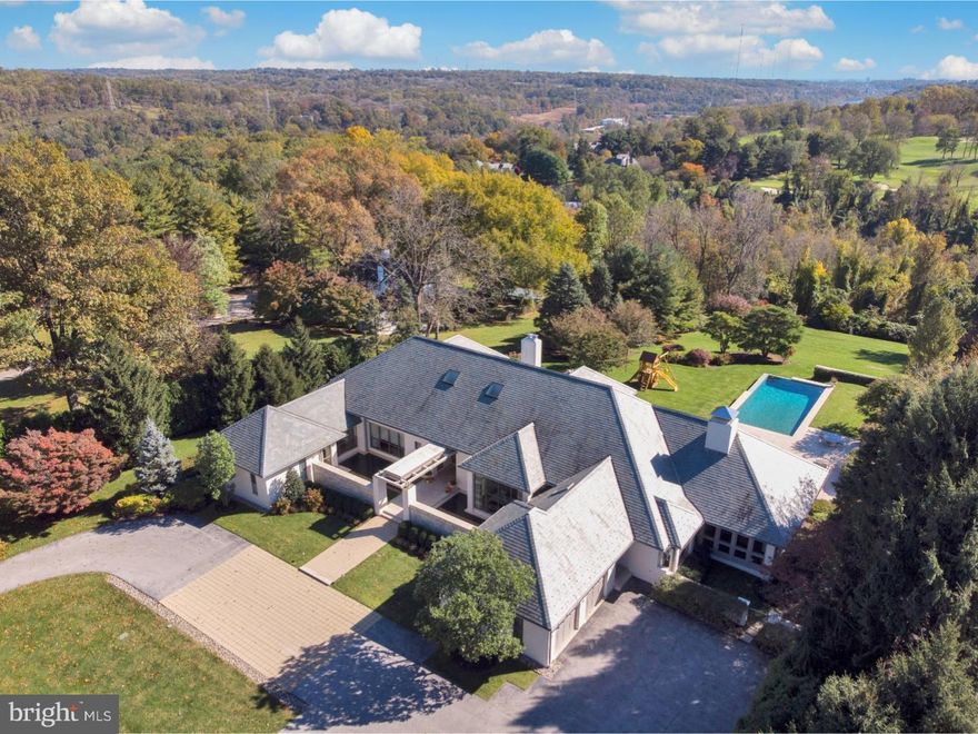 This custom built transitional-style home on 2+ acres is one of the most exceptional residences on the Main Line, offering breathtaking views of the Philadelphia Country Club golf course. Down a private lane, beyond a gated entrance sits an architectural gem with a clean modern fa ade, abundant walls of glass and front courtyard with reflecting pools. Lovely gardens, generous outdoor terraces, a built-in hot tub and infiniti edge swimming pool are all enjoyed in a private, serene setting. Two different living areas ? both with separate entrances ? comfortably accommodate guests or staff.   A vaulted sky-lit reception area introduces a refined, airy interior, where voluminous spaces are bathed in natural light. The sun-drenched vaulted living room & open dining room showcasing spectacular views through glass walls leading out to the spacious rear terrace. A Bulthaup chef's kitchen with commercial grade appliances, quartz counters, island & backsplash & breakfast area overlooking the grounds are thoughtfully designed for daily comfort & large catered gatherings. The beautiful family room & adjacent sunroom have dramatic vaulted wood ceilings & fireplaces.   Positioned separately on the main level is the luxurious master retreat with bedroom, a sitting room with terrace, his & hers spa baths & custom dressing rooms. Completing this level is a second en-suite bedroom with walk-in closet, marble bath, catering kitchen, designer powder room, mudroom & oversized 2-car garage. Upstairs presents 2 additional en-suite bedrooms on private wings with wonderful views & lovely baths. The finished lower level has a recreation room, home theater, sitting room, exercise room and laundry.  An apartment with kitchenette and marble bathroom offers separate egress. Mirroring the design of the main home with extensive use of glass is the gracious guest house with a sleeping area, custom kitchen & full bath. The extraordinary location is near all amenities, major transportation routes & award-winning Lower Merion Schools.