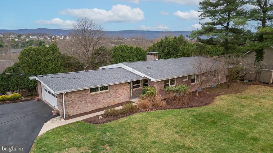 Tucked at the end of a quiet dead-end street with sweeping views of Mount Nittany, this striking mid-century modern home is full of character and style. Large picture windows and 10’+ vaulted ceilings flood the main level with light, while hardwood floors and a dramatic double-sided fireplace anchor the open living and dining spaces. The unique floor plan includes three private bedroom suites on the main level, each with its own full bath — perfect for guests or multi-generational living. The lower walkout level adds flexibility with a fourth bedroom, full bath, a spacious recreation room, and a second fireplace for cozy evenings. The kitchen has tons of storage and opens to the elegant dining area.  The large deck overlooking Mt Nittany is ideal for morning coffee with sunrise views or evening entertaining. With its bold architectural lines, warm mid-century vibes, and a location that blends privacy with convenience, this home is a true hidden gem.