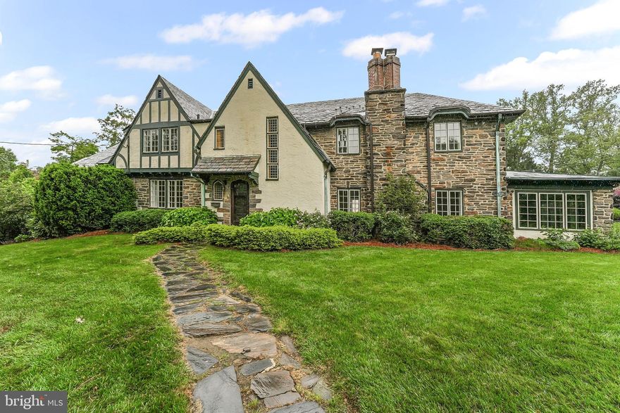 Welcome to this enchanting stone Tudor residence, rich with timeless charm and architectural detail. This spacious home offers 5 bedrooms and 3.5 bathrooms, blending classic elegance with modern comfort. Step through the front door into a gracious marble-floored foyer, highlighted by a curved staircase. Beautiful hardwood floors run throughout, adding warmth and character.
The inviting living room features a wood-burning fireplace and French doors which lead to the sunroom. A formal dining room showcases crown moulding and recessed cove lighting, while the adjoining kitchen and breakfast room offer a cozy space for casual meals. A convenient powder room completes the first floor.
Upstairs, the primary suite offers a sitting room and en-suite bath. Four additional bedrooms, two hall bathrooms, and an upstairs laundry area provide comfort and practicality for everyday living.
The finished lower level includes a generous family room with a fireplace, along with ample unfinished storage space and mechanicals.
Outside, enjoy a beautifully landscaped yard with mature plantings, perennial gardens, and a stone patio overlooking a tranquil creek—a serene setting for outdoor gatherings.
Located just moments from Whole Foods, Suburban Square, top-rated schools, local parks, and convenient access to SEPTA’s Regional Rail and High-Speed Line, this exceptional property combines elegance, space, and an unbeatable location.