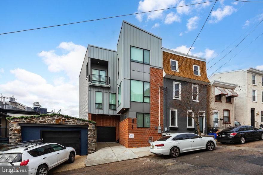 A true Manayunk Masterpiece. Welcome to your dream home in the vibrant and trendy neighborhood of Manayunk, Philadelphia! This 4-bedroom, 3.5-bathroom  home offers an impressive 3,300 square feet of modern luxury, impeccable design, and unparalleled city living. Built in 2021, this new construction home is still very much young. Offering 6.5 years left on its tax abatement! Key Features - Expansive Layout: The thoughtfully designed open-concept floor plan boasts soaring ceilings, oversized windows, and sleek finishes throughout. Chef’s Kitchen: The gourmet kitchen is a centerpiece of the home, featuring premium quartz countertops, high-end stainless steel appliances, a large island with seating, and custom cabinetry—a true haven for culinary enthusiasts and entertainers alike. Bright and Airy Living Room: The spacious living area flows seamlessly from the kitchen and dining space, offering the perfect setting for gatherings or relaxing evenings. Private Retreats: The primary suite is a true oasis, complete with a walk-in closet, a spa-inspired en-suite bathroom with a soaking tub, dual vanities, and a glass-enclosed shower. Three Additional Bedrooms: Generously sized bedrooms on the upper levels provide flexibility for guests, a home office, or family needs. Outdoor Living: This home is an entertainer’s dream, featuring two private balconies and a rooftop deck with sweeping views of the Philadelphia skyline. Enjoy sunsets, city lights, and outdoor lounging in style. Convenience & Comfort: A private garage and driveway offer ample parking—rare for the area—while a modern mudroom and laundry area ensure everyday convenience. Nestled on a quiet street yet steps away from all that Manayunk has to offer, this home perfectly combines modern living with urban convenience. Whether you’re hosting on your roof deck or exploring the lively neighborhood, this property is the ultimate city retreat.  Don’t wait—schedule your tour today and envision life in this incredible home!