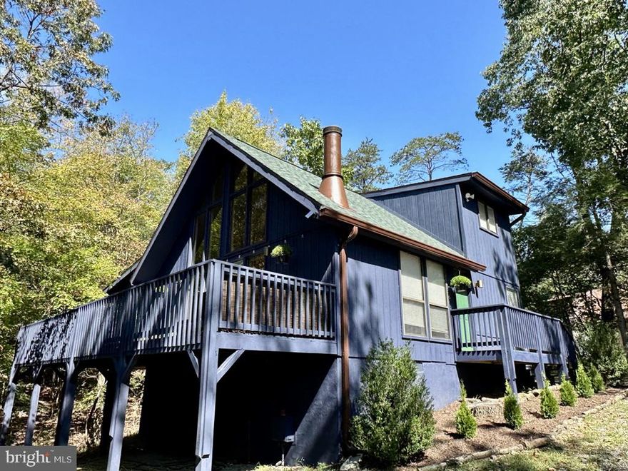 Price improvement - selling unfurnished!  Open house this Sunday! 10/08 12-4pm!  Located less than two hours from DC and Baltimore, this stunning chalet sits on the coolest lot.  It has it's own "holler" (we call it Deer Holler) where the deer hang out constantly. Private and secluded (you can really only see one other house) at the end of a cul-de-sac, it's 1215 square feet of yummy.  The house was recently given a facelift  - new muted green architectural shingle roof and new skylight, painted inside and out. Small fenced yard for the pups to run out and do their biz without having to always go for a walk.  And that exterior paint??? Right? Sherwin Williams Naval. Serene and powerful, it just pops against the green of the trees. At the heart of the home is a killer pellet stove - that literally will heat the entire house. Hardwood floors, updated kitchen with stainless, three bedrooms (primary is in the loft) and two fulls baths make this a place you can spread out and take in nature. High speed internet via Comcast Xfinity makes it a great place to work remotely.  The house has a crawl space great for storing holiday decorations, golf clubs, kayaks etc. It lives mighty and large - great closets, and my oh my... that wall of windows is simply divine.  The house is on public water and has a grinder pump into public sewer.  Central air and heat and this biggest bestest washer and dryer around! For an extra (roughly) $1500 a year, you can continue the B membership to the gym and the pools.  Oh and this is kind of unheard of out here, but you can WALK to the Mountain View Pool, and the Grille to grab some fries or a cocktail.  It will cover your costs if you short term rent it - but also perfect for full-time living out here. Owner/agent has lovingly cared for and updated this baby, and now time to hand her off to the next soul that wants to enjoy nature and the solitude of wild, wonderful and wacky West Virginny . We did an inspection and are handling most of the items on there.  10 mins from a CJ's (a cool locals dive, ) Traver's convenience store and the ever-present Dollar Store, 10-15 from the post office, 18 mins from the Martin's supermarket and 25 mins from Martinsburg where you'll find all the conveniences of the city (and some you'e never heard of!!) Farm markets, breweries, distilleries,  and the best part.... the coolest most diverse neighborhood around. Come make yourself at home in the Woods. House was airbnb'd off and on, in between our friends and family using it. Last year grossed about $35K. Covered all expenses.