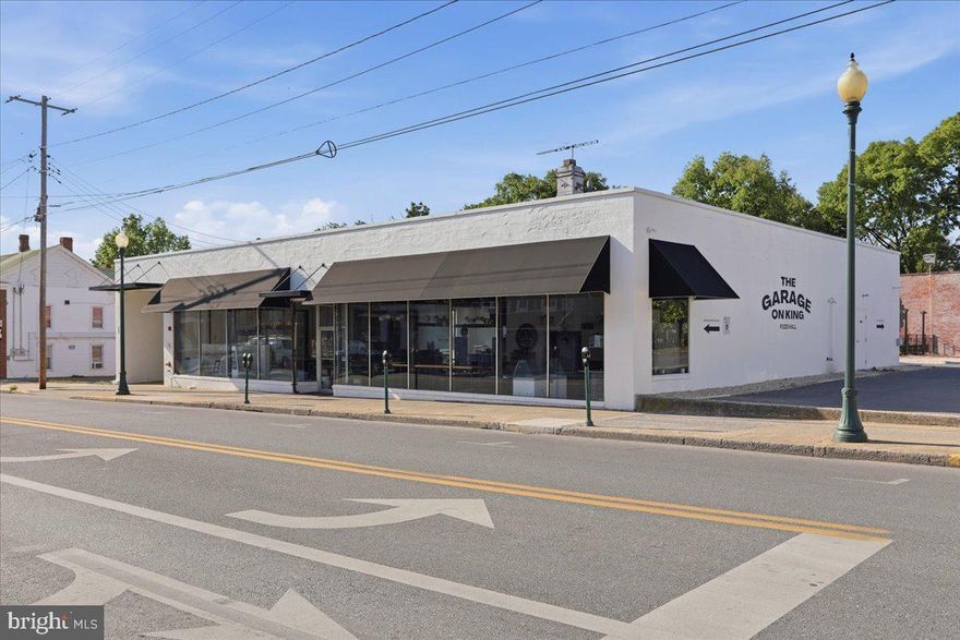 Located in the heart of downtown Martinsburg, 419 W King Street—formerly operated as Garage on King—offers a rare opportunity to acquire a fully renovated commercial property with exceptional flexibility and character, including the potential transfer of the “Garage on King” intellectual property and branding with the sale. Originally built in 1931, this impressive 22,664 (+/-) square foot building features durable concrete block and brick construction, a rubber roof, upgraded commercial electrical systems, new HVAC, and extensive interior renovations throughout. Previously utilized as a dining hall and event venue, the property includes a café, full bar, show kitchen, seven food stall/commercial kitchen spaces, and four restrooms, making it well-suited for hospitality, entertainment, retail, or adaptive mixed-use redevelopment. The industrial-inspired interior showcases exposed brick walls, exposed steel beams, and modern finishes that create a distinctive atmosphere full of charm and functionality. A newly added 2,100 (+/-) square foot paver patio with metal railing expands the venue outdoors for dining, events, or entertainment space, while approximately 20+ on-site parking spaces and multiple access points enhance convenience and accessibility. With all public utilities available—including electric, gas, cable, public water, and sewer—this one-of-a-kind property presents endless possibilities within the City of Martinsburg.