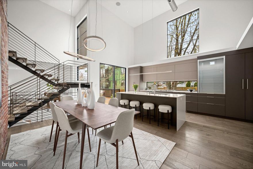 Open House Sun, April 12th  1-4pm
Welcome to Arlington's Modern Loft Style Home! Architecturally Distinct Residence – Fully Renovated w/ Designer Finishes & 20' ceilings!
This exceptional contemporary home seamlessly blends striking architecture with refined European craftsmanship. Fully renovated with a second-floor addition in 2017, the residence offers bold design, premium materials, & thoughtfully engineered storage throughout.
The main level  showcases a dramatic open loft aesthetic with exposed modern ductwork, discreet LED recessed lighting, & a stunning custom floating metal staircase designed & fabricated by a sculptor artist, featuring solid 2-inch oak treads. A breathtaking 20-foot restored exposed brick fireplace serves as the home’s original architectural centerpiece. Premium Western all-aluminum windows paired with Windsor windows bring in abundant natural light, complemented by Hunter Douglas blinds throughout. A whole-home integrated audio system extends to the kitchen, living room, TV room, & deck.
Custom built-ins elevate everyday living, including bespoke cabinetry by Leicht (Germany), custom coat & shoe storage with motion-activated lighting, dedicated vacuum storage, decorative open shelving with track lighting, & thoughtfully designed organizational systems.
The luxury European designer kitchen by Leicht (Germany) blends striking aesthetics with exceptional functionality. Fully paneled appliances maintain a seamless look while precision-engineered cabinetry maximizes storage with a pull-out pantry system, full-extension spice rack, concealed glass appliance garage, & custom interior drawer fittings. Imported German countertops & a dramatic waterfall island anchor the space. Architectural details include a flush backsplash window overlooking the garden, integrated adjustable lighting with remote dimming controls, LED soffit lighting, & a BEST commercial-grade concealed exhaust system.
The dining area is highlighted by sculptural designer light fixtures suspended dramatically from the 20-foot ceiling & positioned at an artistic angle to complement the architecture.
The main level bathroom features a freestanding vanity with quartz countertop, vessel sink with black brass touch-activated faucet, black bronze designer shower fixtures, & a Duravit dual-flush toilet. The space is finished with award-winning “Fossil” porcelain tile by Refin Ceramiche (Italy) inspired by prehistoric ammonite patterns, paired w/large-format Italian porcelain flooring & SONNEMAN designer lighting.
A main level bedroom includes custom oak shelving crafted by a local artisan & a modular wall storage system.
Upstairs, the primary suite offers a peaceful retreat with a custom wardrobe featuring sleek sliding glass doors, a fully outfitted wardrobe system, built-in dressing table positioned for optimal natural light, integrated audio speakers, & a ceiling fan.
The spa-inspired primary bathroom features a floating Duravit double-sink console w/ minimalist cabinetry, real wood-textured surfaces, ceramic basins, and a Duravit toilet with WonderGliss water-repellent coating. The wet area includes a freestanding jetted soaking tub and glass-enclosed shower. Statement “Folded” wall tile by Mutina Milano (Italy) creates sculptural dimension, complemented by large-format Italian porcelain flooring and an oversized flush mirror with modern lighting.
The Jack-and-Jill bathroom features playful Italian porcelain hexagon tile, oversized shower tiles, a wall-mounted Duravit double-sink console with integrated storage, Duravit dual-flush toilet designed by Philippe Starck, and a tub-shower combination.
Additional highlights include a fully organized garage with custom cabinetry (lifetime transferable warranty), durable melamine storage systems, professional slat wall organization, and dedicated bike racks.
Exterior features include Hardie panel and Englert metal siding, a bespoke horizontal cedar fence, architectural lighting, & 2 HVAC's.