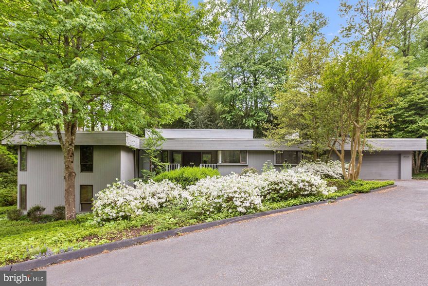 This stunning contemporary home is nestled on a generous lot and enjoys a park like setting with mature trees, plants and flowers that provide tranquility and privacy. A large and open entrance foyer with generous closets is the entry point for this mid-century  masterpiece. A breath taking living room and dining area with soaring ceilings is both elegant and functional. It features a wall of floor to ceiling windows and doors, natural light from two exposures and a fireplace. A spacious gourmet kitchen with table space for six and top of the line appliances is found just off of the dining area. The den is warm and inviting with a fireplace and a wall of windows and doors leading to the private outside deck. A wet bar hidden behind custom cabinetry adds a level of convenience and function to the den. The main level is also home to a generous owner's suite with an office/sitting space, ample closets and en suite bathroom complete with a dual vanity, shower and bath tub. The second bedroom is conveniently situated next to the owner's suite and has a large closet, light from two exposures and an en suite bathroom. The lower level features two impressive multi-function rooms offering tremendous flexibility. The main family room boasts a bar, light from several windows and doors leading to the gardens. Also on this level are two large bedrooms with closets and a full bath. A large two car garage that opens to the kitchen and main level laundry facilities allow for convenient and modern living.  Just steps away is the community swimming pool with club house as well as two lighted tennis courts which serve this boutique enclave exclusively.