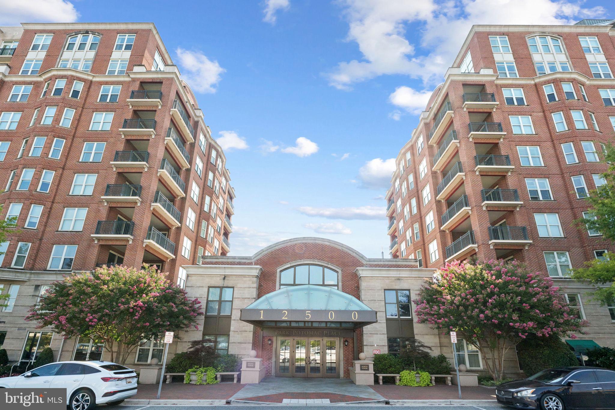 NEW ON MARKET!! OPEN HOUSE SAT, Aug 16th 2-4PM!!
Light-filled penthouse in Park Potomac offering over 2,750 sq ft of well-designed living space. This bright corner unit features high ceilings, 2 bedrooms plus a large den, and 2.5 baths. Enter the oval foyer into the grand, open living and dining rooms for the first “wow” factor. Behold soaring curved ceilings and oversized windows with double doors leading to a wide balcony. The spacious kitchen offers a breakfast area, seated center island, and relaxation space. The den is exceptionally large and features custom built in shelving and lighted display cabinets. A spacious primary suite includes a walk-in closet, additional double-door closet, and marble bath with separate tub and walk-in shower with seamless glass door. Additional highlights include upgraded flooring, electric shades, custom built-in shelves and a large laundry room. Two garage spaces and storage are included, with two more spaces available for purchase. Furnishings may be sold separately.
This full-service building with 24-hour security, concierge, fitness center, outdoor pool, multiple seating areas, tot lot, library, and party room. All just one block to grocery, dining, and shops of Park Potomac!