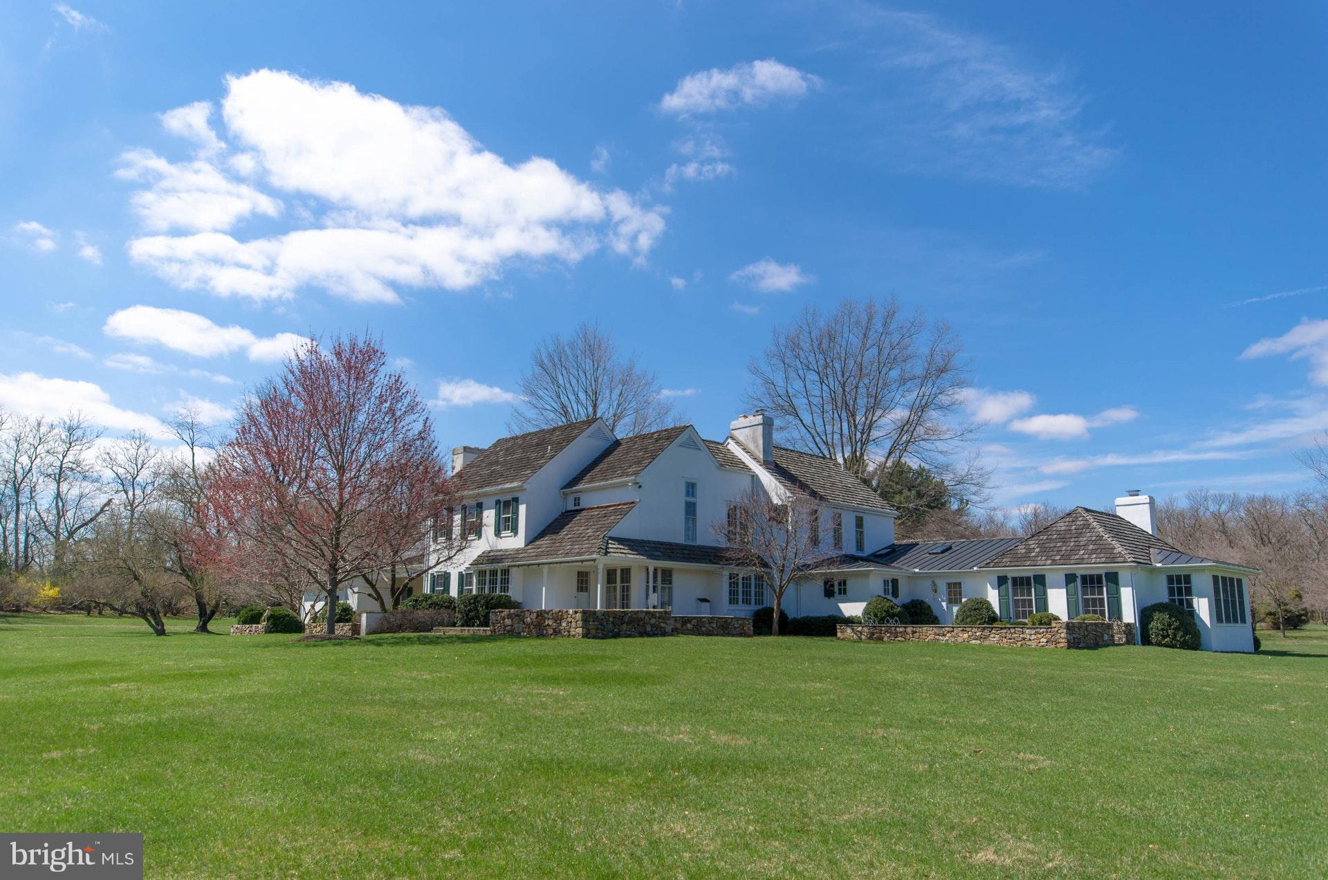 One of the most noteworthy properties to come on the market in a generation, this exceptional residence is nestled in the enviable environs of the country club's private golf community. Gracefully positioned in the middle of 13 acres, the home sits amidst mature landscaping and perennial gardens, in a setting graciously embellished by time. The property is reminiscent of the stunning country homes of the British Isles, surrounded by fields of green, enticing one to walk the acreage and stroll the lane. A re-imagined antique classic, the house is executed with exceptional craftsmanship. The timeless design is a blend of classic details with contemporary spaces, creating an ambiance that bespeaks sophistication without formality. Well-hidden down a long drive, the approach opens to a special retreat that is perfectly private. Pastoral views surround the house and include a handsome lawn with stately pines, an open field and a rear copse of hardwoods. At the far end of the lawn is a playhouse, designed to reflect the main house, enticing young and old to explore. The acreage is made up of specimen plantings and impressive hardscaping. Formerly the nursery property for Bethlehem Steel, there is a stately old world feel, and a whimsical, inviting ambience. At the center of all, the bespoke design captures an elegance one would expect in a quintessential Saucon Valley estate property, where exquisite craftsmanship and detailed execution define each room. Offering custom millwork, moldings, doors, locks, and hardware, there are 7 fireplaces and a bounty of nine-over-six windows for great natural light. The main entry hall is flanked by an intimate formal dining room and a beamed keeping room with a colonial brick fireplace, historic Bethlehem brick, antique barn board walls, and superb views. The foyer is also entrance to an expansive formal living room with fireplace, accommodating multiple seating areas and accessing a large bluestone patio and adjacent den with fireplace. Throughout its history, the home has hosted significant gatherings with ease. A family room addition boasts a trussed, vaulted ceiling, built-in desk and bookcases, a custom bar, and tall windows with stunning views. There are antiqued wood floors, walls of built-ins, wide window seats, beamed ceilings, and attention to detail like no other, throughout every floor. A back hallway, with Jerusalem stone, leads to a side terrace and a luxurious 1st floor master bedroom suite with fireplace, Jerusalem stone bath and large dressing area and cedar closet. This first floor master suite offers a high ceiling, fireplace, built-ins, window seating, and access to a private bluestone terrace with landscaped gardens and vistas of the acreage beyond. On the second floor there is a second master suite with fireplace, and an additional 3 bedrooms, one with fireplace, and 3 full baths. Finally, as further complement to this classic estate, the guest house is enchanting on a misty morning and as fireflies gather at night. It offers character-filled living spaces for overflow guests and family, boasting kitchen, living room with fireplace, garage and bedroom suite. In this field of dreams, only the abundant wildlife breaks the stillness. Includes 6.6 acre lot.