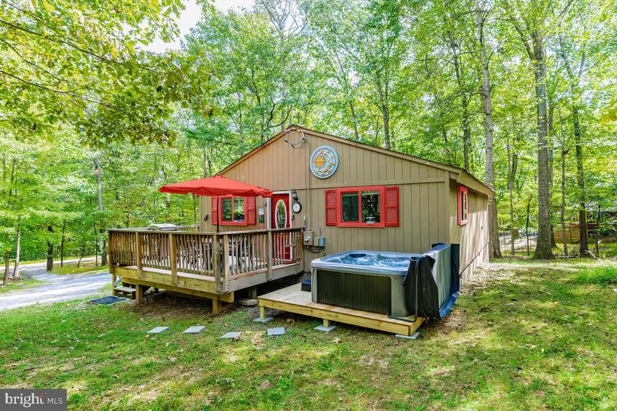 Recently remodeled cottage nestled in The Woods Resort, just minutes from downtown Berkeley Springs!  Features an open floor plan living and dining with rich hardwood floors and a thoughtfully updated kitchen complete with stainless steel appliances.  Outside you’ll find a wraparound deck, small pond, and brand new hot tub.  The seller spent over $44,000 upgrading the property.  As a vacation rental it has generated rental revenue consistently for nearly three years ($47,000 over the past year alone), and can come with an existing property manager and cleaner.  This cabin has class B membership in The Woods Resort community, and includes access to an 18-hole golf course (with low green fees), indoor & outdoor pools, fully-stocked gym, tennis & sports course, a spa, a restaurant and pub, and miles of walking/hiking trails.  Hot tub and furniture optional, available for purchase.  See seller docs for a summary of rental history  & financials, and more info about The Woods.  $1,000 buyer credit if you continue using the same property manager.  Perfect vacation home or investment property!