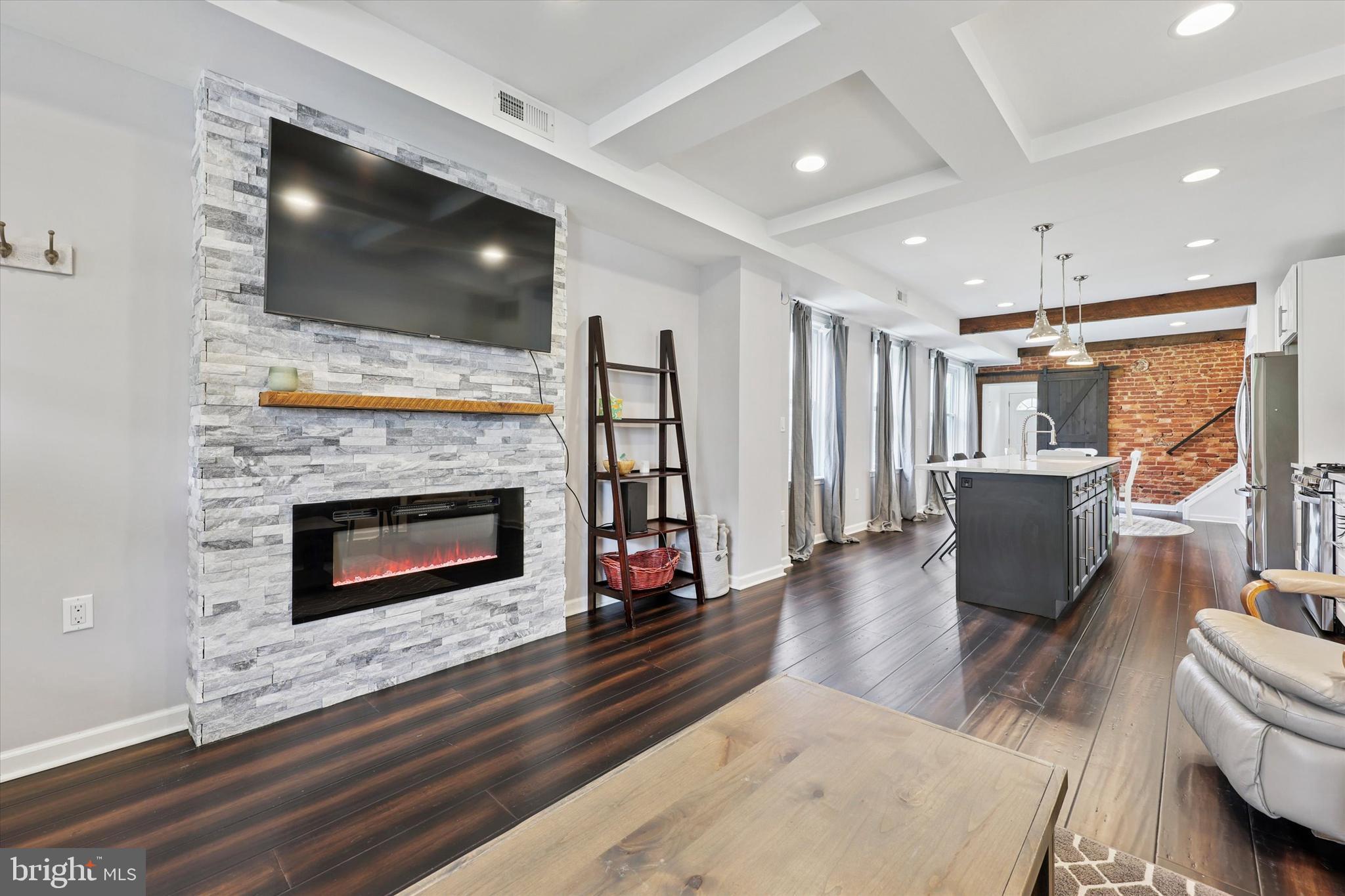 Move right in to this FULLY renovated 4-bedroom, 2.5-bath brick twin, that offers a perfect blend of modern updates and classic charm. Located on a lovely, quiet and walkable street, with ample parking, this home is just steps from Gorgas Park, local shops, trails, and public transportation, with easy access to Center City, King of Prussia, the Blue Route, and nearby colleges, this home offers the ideal combination of comfort, style, and convenience. This home features an inviting covered front porch, a stunning open-concept floor plan designed for today's lifestyle as well as a great rear yard space! Step inside to find engineered hardwood flooring, exposed brick accents, coffered box ceilings, and recessed lighting throughout the main level. The spacious living room boasts a color-changing electric fireplace set against a dramatic stacked stone wall—ideal for cozy nights or entertaining guests. The gourmet kitchen is a showstopper with a 10-foot quartz island seating four, white shaker cabinets with soft-close drawers and doors, quartz countertops, subway tile backsplash, built-in microwave, and stainless steel appliances, all illuminated by three elegant pendant lights. Adjacent is the dining area, which features a full exposed brick wall and a barn door that leads to a convenient laundry room, powder room, and access to the fenced rear yard—perfect for outdoor living. Upstairs, the second level offers three bright bedrooms with high ceilings and recessed lighting, plus a beautifully updated hall bath with ceramic tile and a tub/shower combo. The third level is dedicated to the private primary suite, complete with a walk-in closet, a luxurious full bath featuring a glass-enclosed shower with a rainforest shower head, and a bonus storage area. The finished basement adds even more living space, along with a newer waterproofing system and two additional storage areas. Be sure to check this one out!
