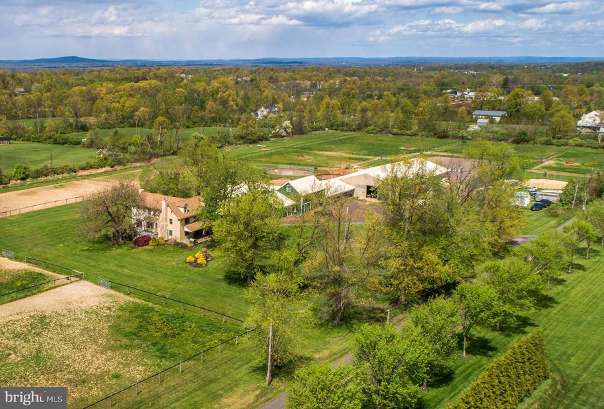 This classic Bucks County farmhouse estate offers a rare opportunity to own a fully equipped equestrian property set on nearly 13 picturesque acres in Hilltown Township. Designed with the serious horse enthusiast in mind, the property seamlessly combines a turnkey training facility with the timeless charm of a circa-1780 farmhouse—creating an ideal setting for both horse and rider.
At the heart of the farm is a 60' x 120' indoor riding arena, thoughtfully updated with masonry sand and fiber footing for optimal performance. Complementing the indoor is a 100' x 200' outdoor arena with well-draining footing, providing year-round versatility for training and riding. The well-appointed barn features 23 horse stalls, 4 pony stalls, and a two-stall shed row, along with two tack rooms, a kitchenette, and a bathroom for convenience. Eleven fenced pastures with solar-powered electric fencing allow for efficient rotation and turnout, while a round pen and hot walker support a complete training program. A private trail encircles the pastures, offering the ease of riding directly on your own property.
Above the barn, two beautifully updated apartments—one one-bedroom and one two-bedroom—provide excellent options for staff housing, guest accommodations, or rental income. One includes an enclosed porch, while the other offers a flexible bonus room.
The farmhouse itself overlooks the grounds, offering peaceful views of the pastures and daily horse activity. A welcoming wraparound front porch sets the tone, while inside, the home blends historic character with modern comfort. Wide-plank yellow pine floors, deep window sills, and exposed beams reflect its heritage, while the thoughtfully designed layout supports today’s lifestyle.
The living room features a striking stone fireplace with wood insert, and the dining room includes a built-in mirrored serving cabinet and generous storage. A dramatic floor-to-ceiling stone wall anchors the kitchen, which is equipped with cherry cabinetry, granite countertops, stainless steel appliances, and a bright breakfast area.
The family room, with its raised-hearth stone fireplace, opens to a private 530-square-foot two-tiered deck—perfect for relaxing or entertaining while overlooking the pastures. A mudroom with laundry, located on the barn side of the home, provides a practical transition from stable to house.
Upstairs, the primary suite offers a walk-in closet and a spacious bath with dual vanities, Jacuzzi tub, and separate shower. Three additional bedrooms and a full bath complete the second floor, while a walk-up attic offers expansion potential.
Additional highlights include a new roof (May 2024), updated HVAC systems (2022/2023), a newer oil tank and heater flue, and an electronic dog fence encompassing approximately six acres.
Beyond equestrian use, the indoor arena can easily accommodate storage for equipment, vehicles, or recreational boats. An adjacent equipment shed and a heated/cooled 1.5-car garage with 220 three-phase electric, high ceilings, and bright LED lighting make this property equally appealing for hobbyists or small business use.
Ideally located in the heart of Bucks County—just 5 miles from Dublin, approximately 18 miles from the Bucks County Horse Park, 35 miles from Philadelphia, and 80 miles from New York City—this property offers the perfect balance of accessibility and a private country setting.
Act 319 preferential assessment, which may allow for a one-acre subdivision, offering potential for a second homesite (buyer to verify). 24-hour notice required.
