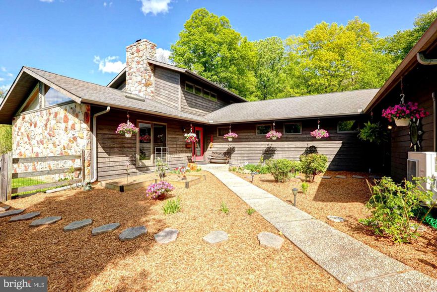 Tucked away at the end of a long, secluded lane, this striking contemporary home offers the perfect blend of privacy, space, and distinctive design. Set on 4.2 beautifully balanced acres of fenced open ground and woods, this property is a rare opportunity to enjoy both nature and modern comfort, complete with walking trails and a serene pond featuring a fountain that can be viewed from the deck. 
The heart of the home is a spacious, light-filled kitchen featuring stainless steel appliances, a center island, exposed beams, hardwood flooring, a wet bar, a pantry, and a charming plant window. Two sets of sliders lead directly to the expansive deck-ideal for indoor-outdoor living and entertaining while overlooking the picturesque pond. A convenient pass-through window connects the kitchen to the dining room, which is highlighted by a large triple window.
The dramatic family room is a true showstopper, boasting a vaulted ceiling with skylights and a stunning stone wood-burning fireplace as its focal point. Sliders open to a small deck offering a beautiful, sweeping view of side of the the property.
The main level includes three generously sized bedrooms—each with its own slider access to the decking. A full bath located down the hall services these bedrooms, while a conveniently placed powder room (half bath) and laundry room complete the main floor.
Upstairs, the private primary suite offers a peaceful retreat with a walk-in closet, full bath, many windows, and a versatile loft space accessed through a stylish barn door. The loft features two skylights and offers excellent cross ventilation, enhanced by mechanically operated windows, making it an ideal space for a home office, gym, or relaxation area.
The walkout lower level expands the living space even further and is perfectly suited for multi-generational living. Featuring French doors that lead to a covered patio with a hot tub area as well as a concrete firepit pad. This level includes a comfortable living space, kitchenette, full bathroom, and an additional flexible room currently used as a train room. There’s also a dedicated exercise room with cork flooring, a workshop with multiple windows, and a unique bunker-style storage area. The workshop includes secondary stair access to the garage, while the primary access to the garage is located on the main level. Whole house Central Vacuum!
Car enthusiasts and hobbyists will appreciate the oversized three-car garage, complete with heating and cooling, an epoxy floor, utility sink with hot and cold water, and direct access to both the home and garden. A compressor is also included with the property. Expanded driveway parking fitting multiple vehicles as well as a 2 car carport.
Additional highlights include ceiling fans in all bedrooms, a whole house generator for peace of mind, and a charming courtyard entrance adorned with mature plantings and seasonal blooms. The house is a certified wildlife habitat. Large Shed for all things outdoor. 
This one-of-a-kind property in the Avon Grove school district offers exceptional versatility, privacy, and character—an ideal setting for those seeking something truly special. Easy access to the Jennersville Shopping Center with a grocery store, restaurants and other conveniences. and Rt1. Christiana Care Hospital is just a few miles away.