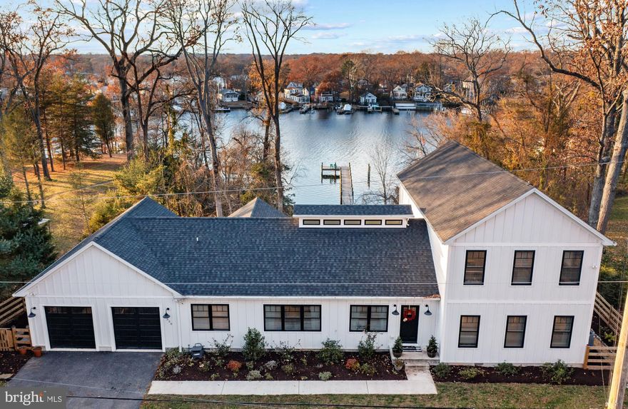 This gorgeous modern farmhouse, ideally sited at the end of a quiet drive, along the picturesque shores of the Magothy River is a true masterpiece. This home was meticulously rebuilt in 2019 from the foundation up, and every detail has been carefully crafted to create a home that seamlessly blends sophistication with the tranquility of waterfront living.  As you step through the front door, you are greeted by an expansive waterfront view that sets the tone for the entire residence. The open floor plan on the main level boasts luxurious vinyl plank radiant heated floors, a gas fireplace with custom built-in surround, and vaulted ceilings with skylights that fill the space with natural light. Glass doors lead you to a meticulously designed waterfront backyard patio, perfect for enjoying the stunning views and entertaining guests. The gourmet kitchen is a chef's dream, featuring quartz countertops, a subway tile backsplash, and an oversized quartz island with seating. Stainless steel appliances complement the modern aesthetic, while a large butler's pantry provides additional convenience with an additional refrigerator, dishwasher, sink, and ample storage. The kitchen seamlessly opens to a spacious dining area, ideal for entertaining. The main level laundry/mudroom, featuring a dedicated dog washing station and built-in storage solutions, add practicality and ease of use.  The main level also accommodates an office, a guest bedroom/den, and a powder room, offering flexibility and convenience. The primary suite is a true retreat, complete with a waterfront view, glass doors to the backyard patio, a serene ensuite bathroom, and a spacious walk-in closet.  Venture to the upper level, where a second laundry area and three bedrooms with walk-in closets await. Two bedrooms share a connecting ensuite bathroom, while another bedroom boasts its own ensuite bathroom and a captivating waterfront view.  The finished attached garage serves as a versatile recreation room, equipped with built-in sink, custom built-in storage solutions and two split units for AC and heat. The bonus room above the garage offers endless possibilities – whether it be an office, gym, or hobby room, all with a water view.  Step outside to the meticulously landscaped .76-acre waterfront property, featuring a pebble and natural stone patio facing the water. Stone steps lead to the sandy beach, and a private dock with one boat slip awaits your maritime adventures. The property also offers the option to add a boat lift with a 6' mean low water.  With its custom designer finishes, thoughtful layouts, and unparalleled waterfront setting, this modern farmhouse is more than a home – it's a lifestyle. Immerse yourself in the beauty of the Magothy River and make this exquisite property your own.