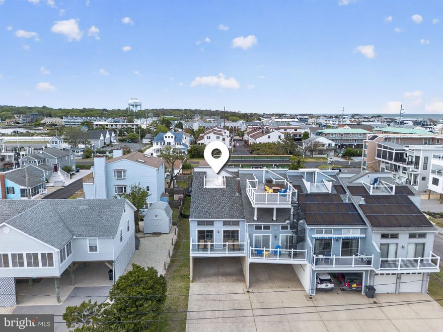 Bay Views & No Condo Fees! Live the ultimate coastal lifestyle in the heart of Dewey Beach. This roomy 4 BR, 4 BA end-unit townhome offers complete independence—you own the land with no condo or HOA fees. The layout features 3 spacious en-suite bedrooms, a great room with vaulted ceilings, a wood-burning fireplace, and a large sunroom serving as an ideal second living space. Relax on the massive rooftop deck with great bay views, or host summer gatherings in your private, fenced backyard perfect for barbecues. Rest easy with a brand-new roof installed in 2024. Parking is a breeze with a covered carport and a long driveway accommodating up to 8 cars. Unbeatable walkable location near the sand, dining, and nightlife. A premier investment or personal getaway!